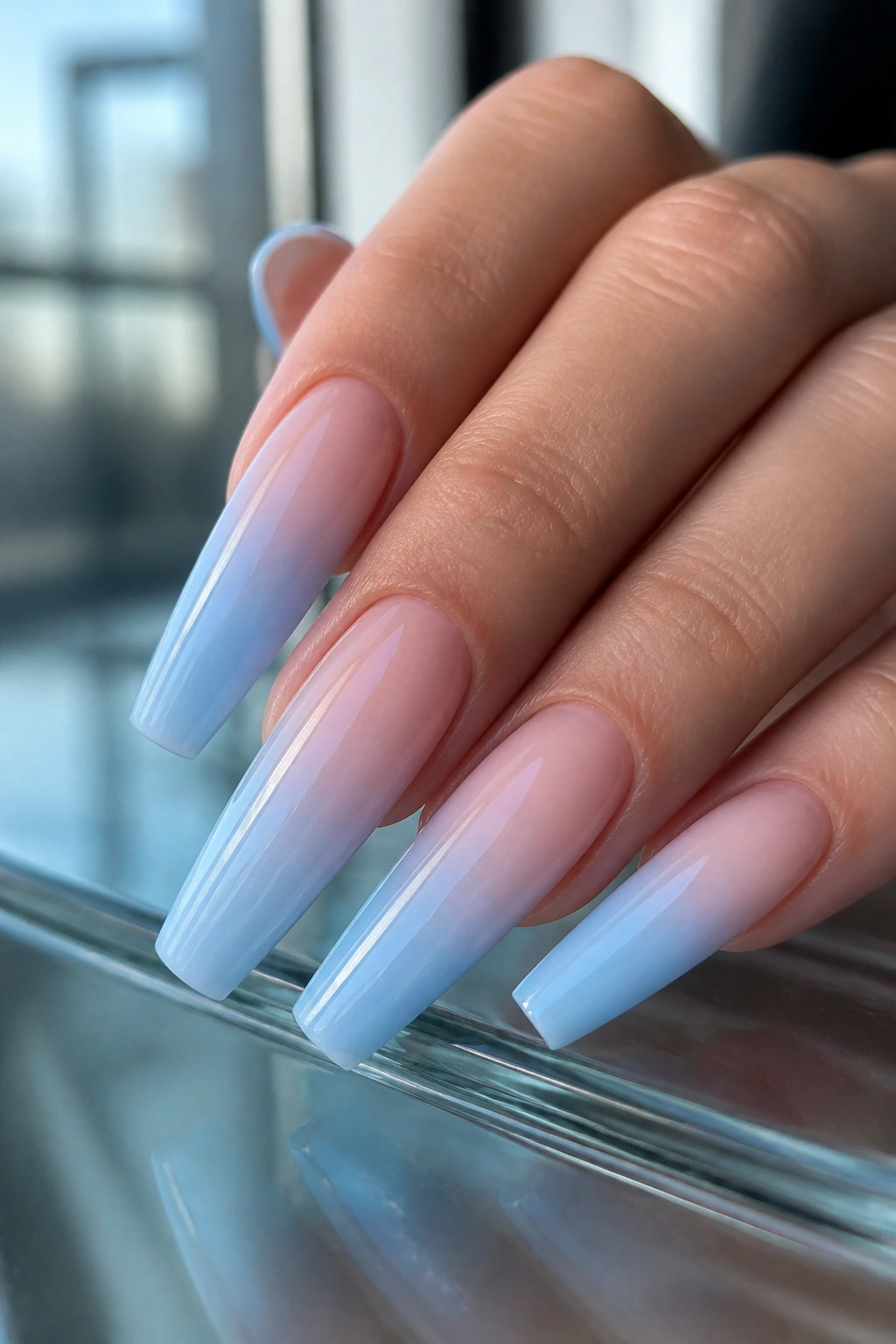 Close-up of long XL coffin nails in baby sky blue ombre with gloss finish