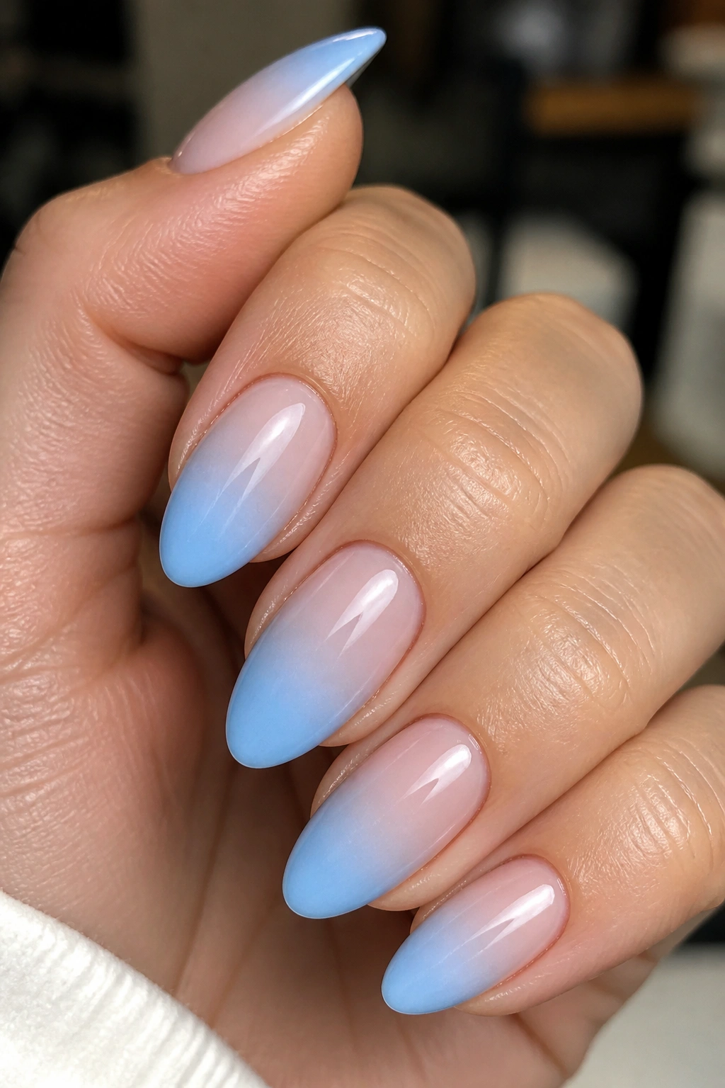 Almond nails baby blue ombre fade on nude base close-up.