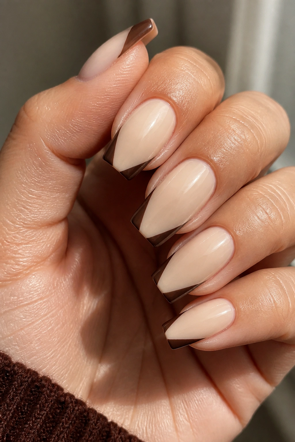 Close-up of beige coffin nails with dark brown corner tips on a real hand