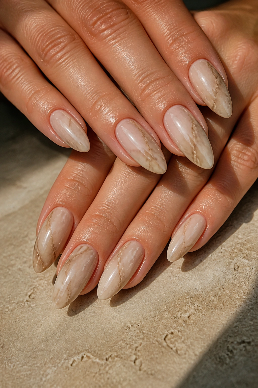 Close-up of almond nails in beige and taupe marble on hands
