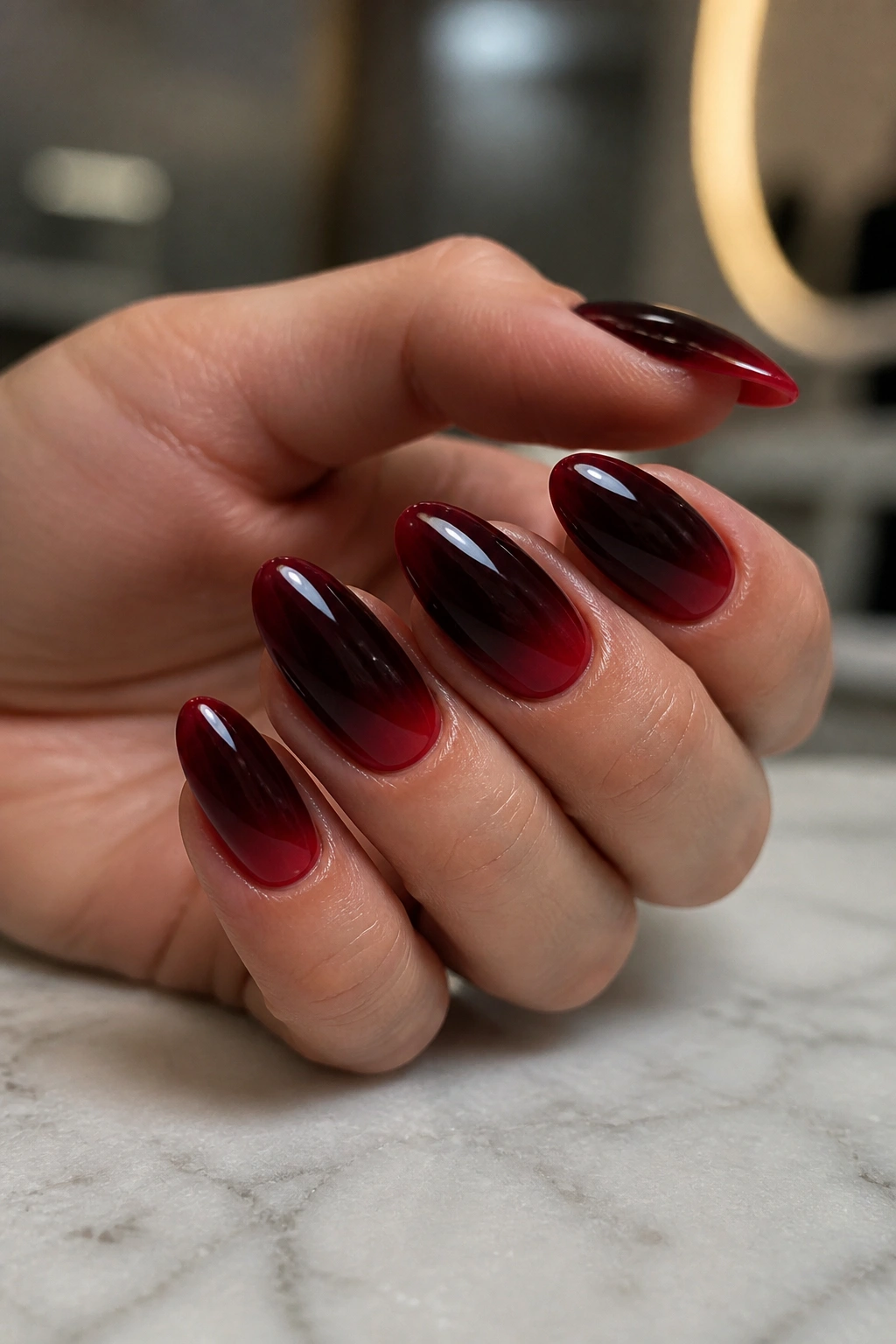 Close-up of almond nails with a black-to-cherry fade on a realistic hand