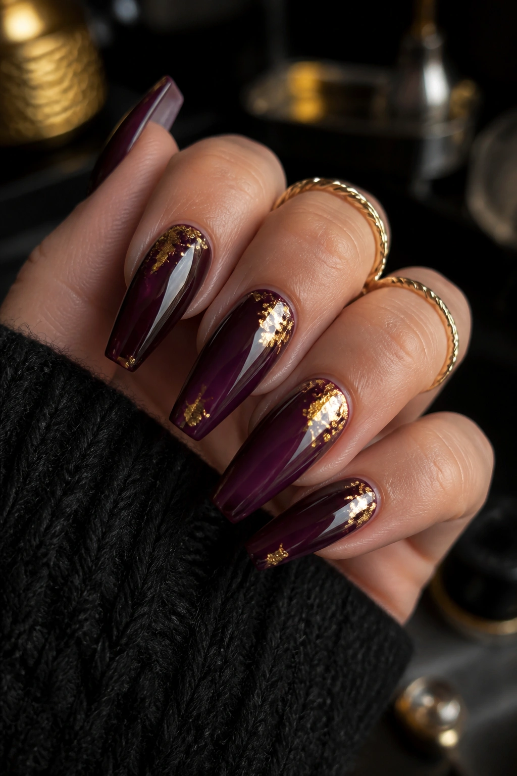 Close-up of black cherry purple nails with gold foil on a real hand