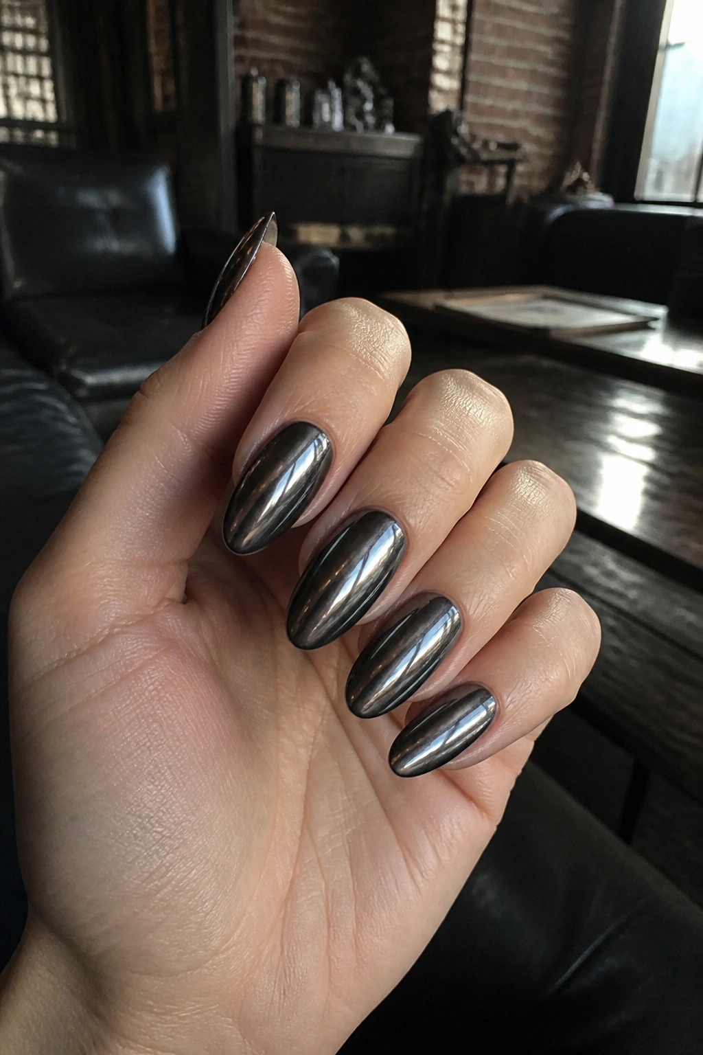 Close-up of black chrome almond nails on a real hand