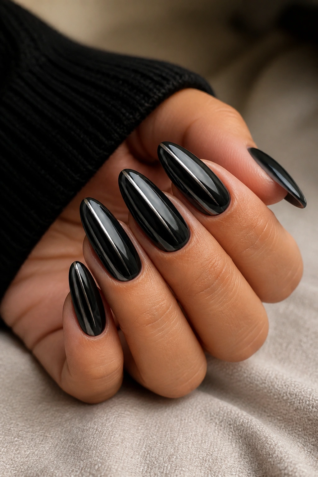 Close-up of real hand showing almond-shaped nails with black chrome and a single side stripe