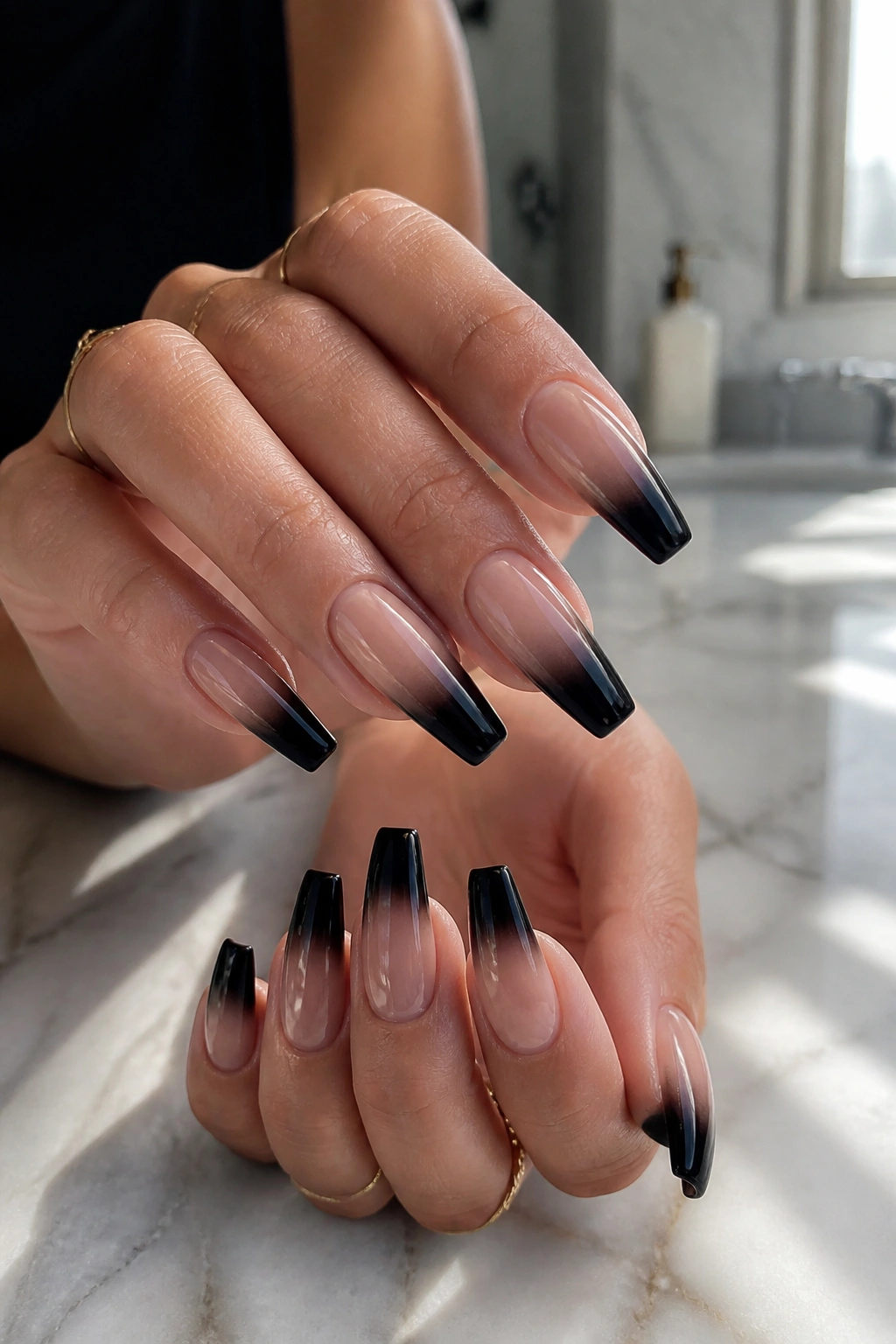Close-up of hands with black fade coffin nails on nude base