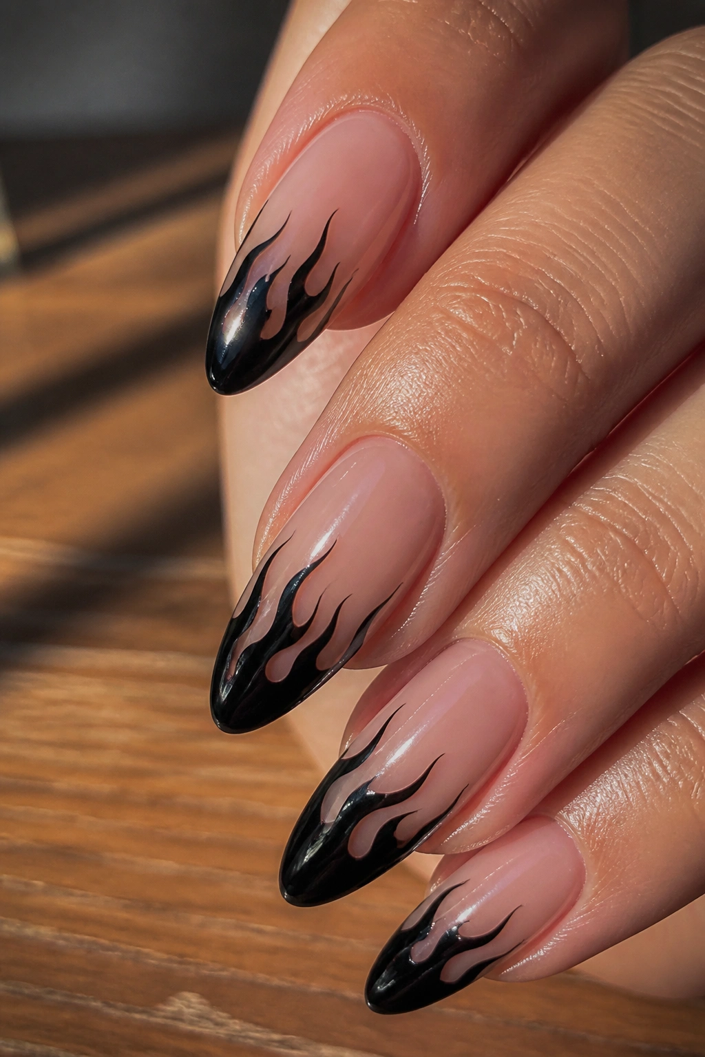 Close-up of almond nails with black flame tips on nude base