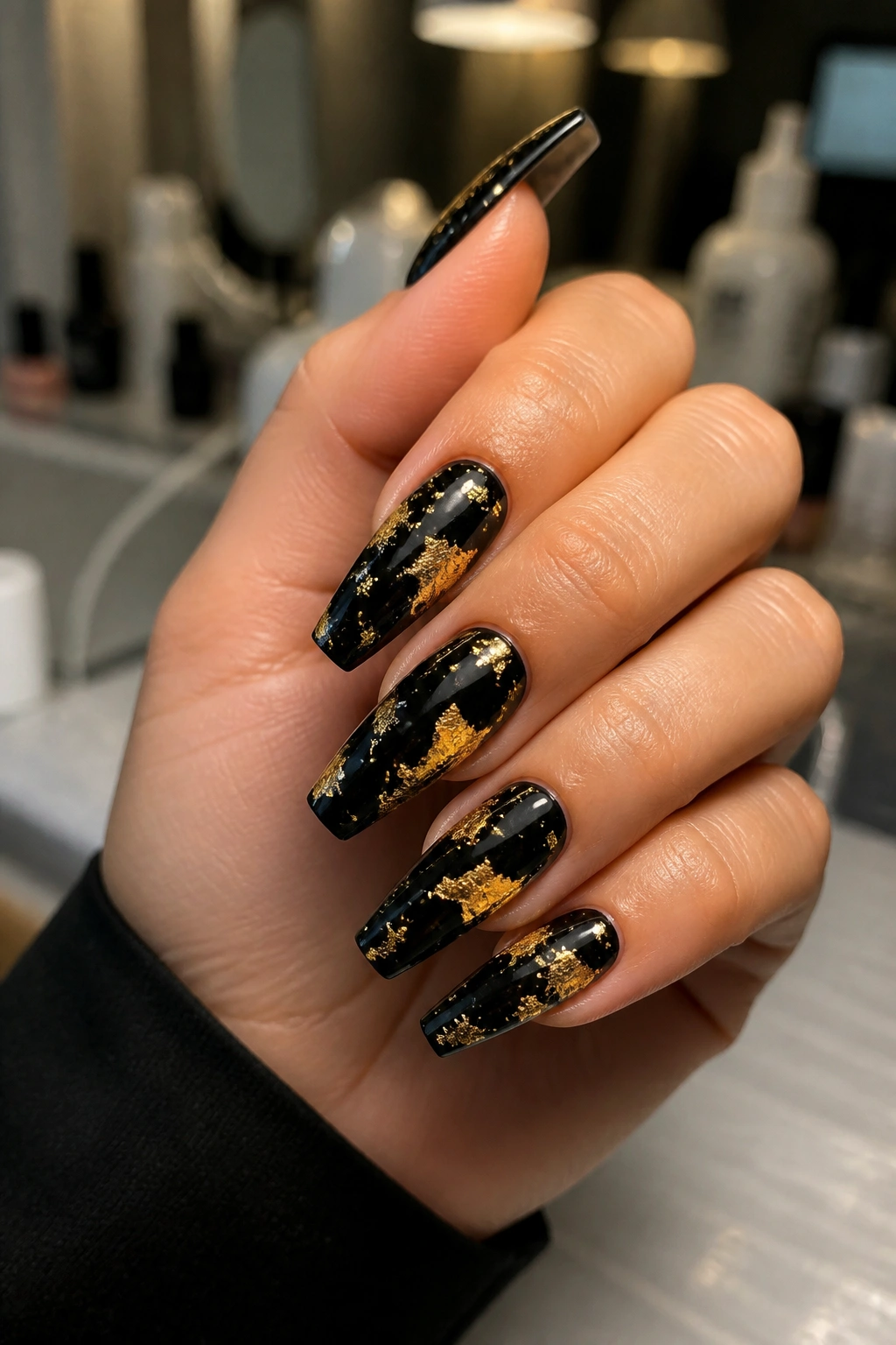 Close-up of black coffin nails with gold foil patches on a real hand
