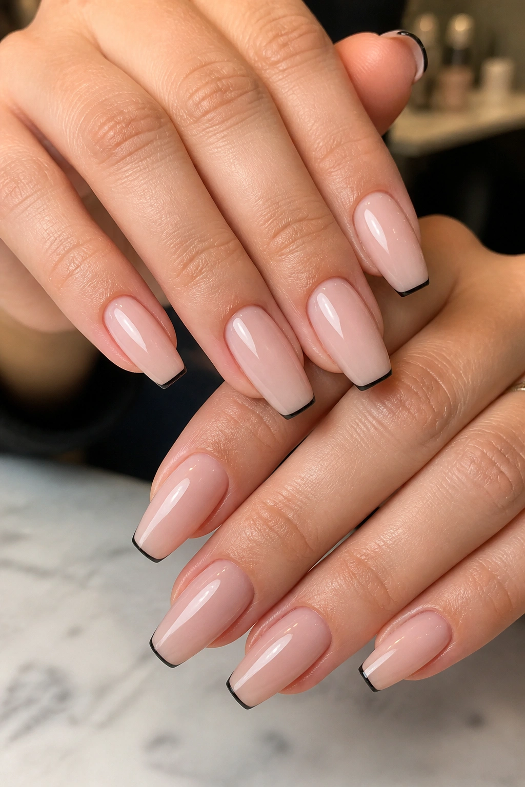 Close-up of medium coffin nails with micro black tips on sheer pink base