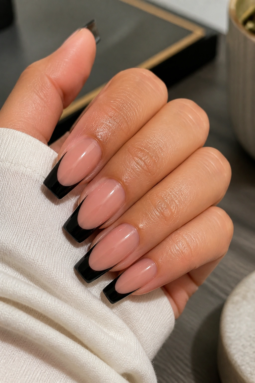 Close-up of coffin nails with black French tips on nude base