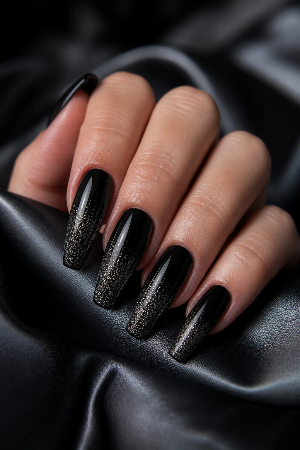 Close-up of black glitter fade coffin nails on a manicured hand