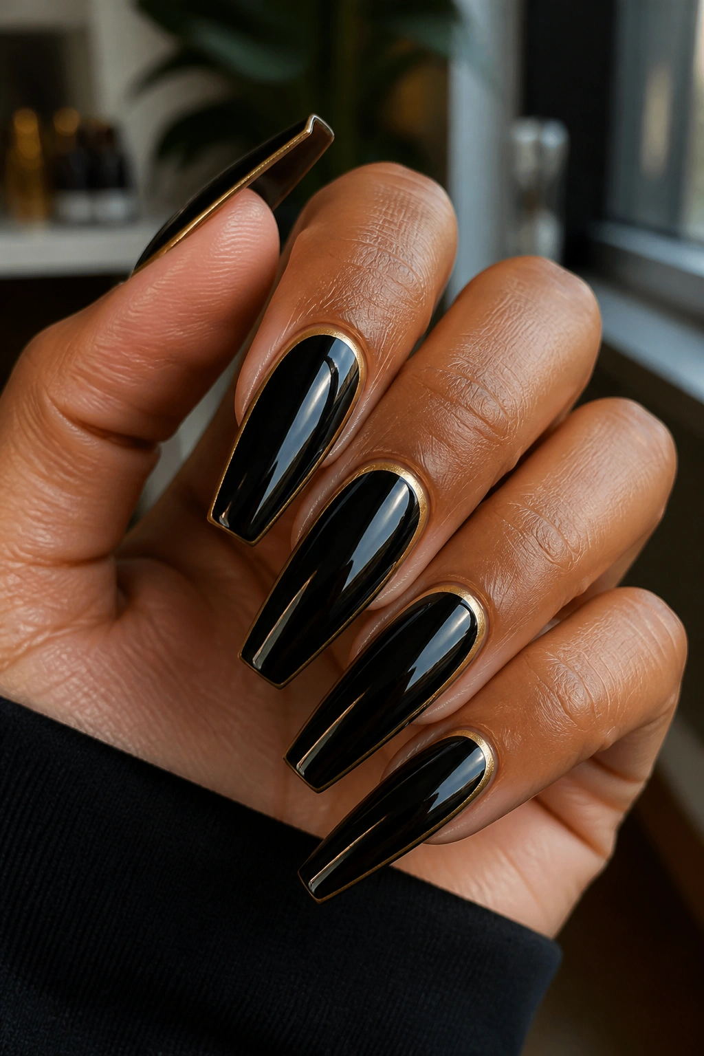 Close-up of black coffin nails with gold line on a real hand in a salon