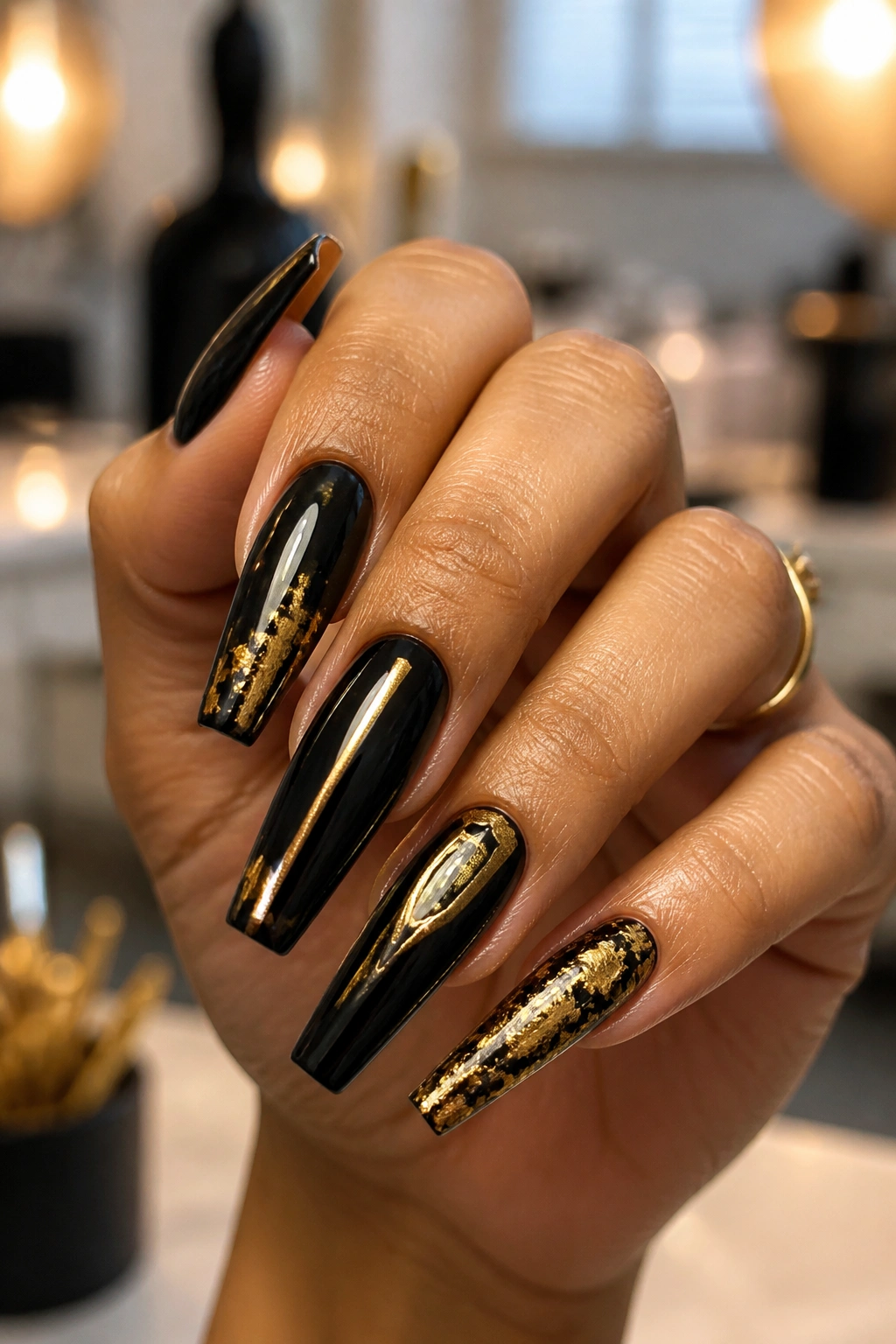 Close-up of a real hand with black and gold coffin nails in a nail salon.