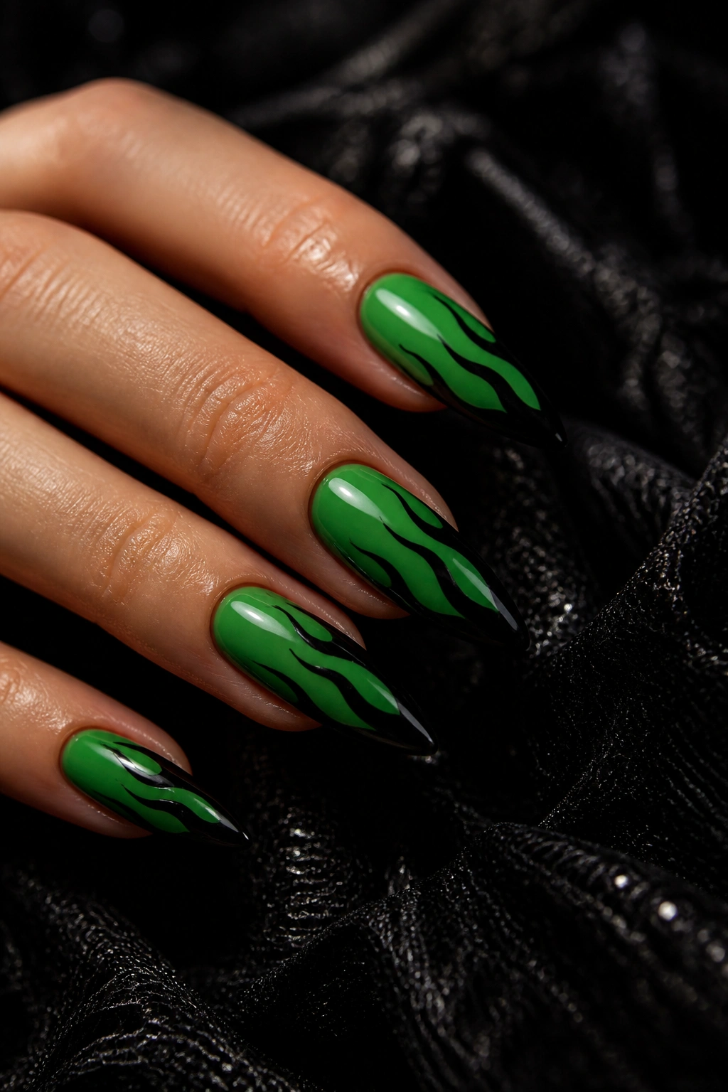 Close-up almond nails with a green base and black accents on a real hand