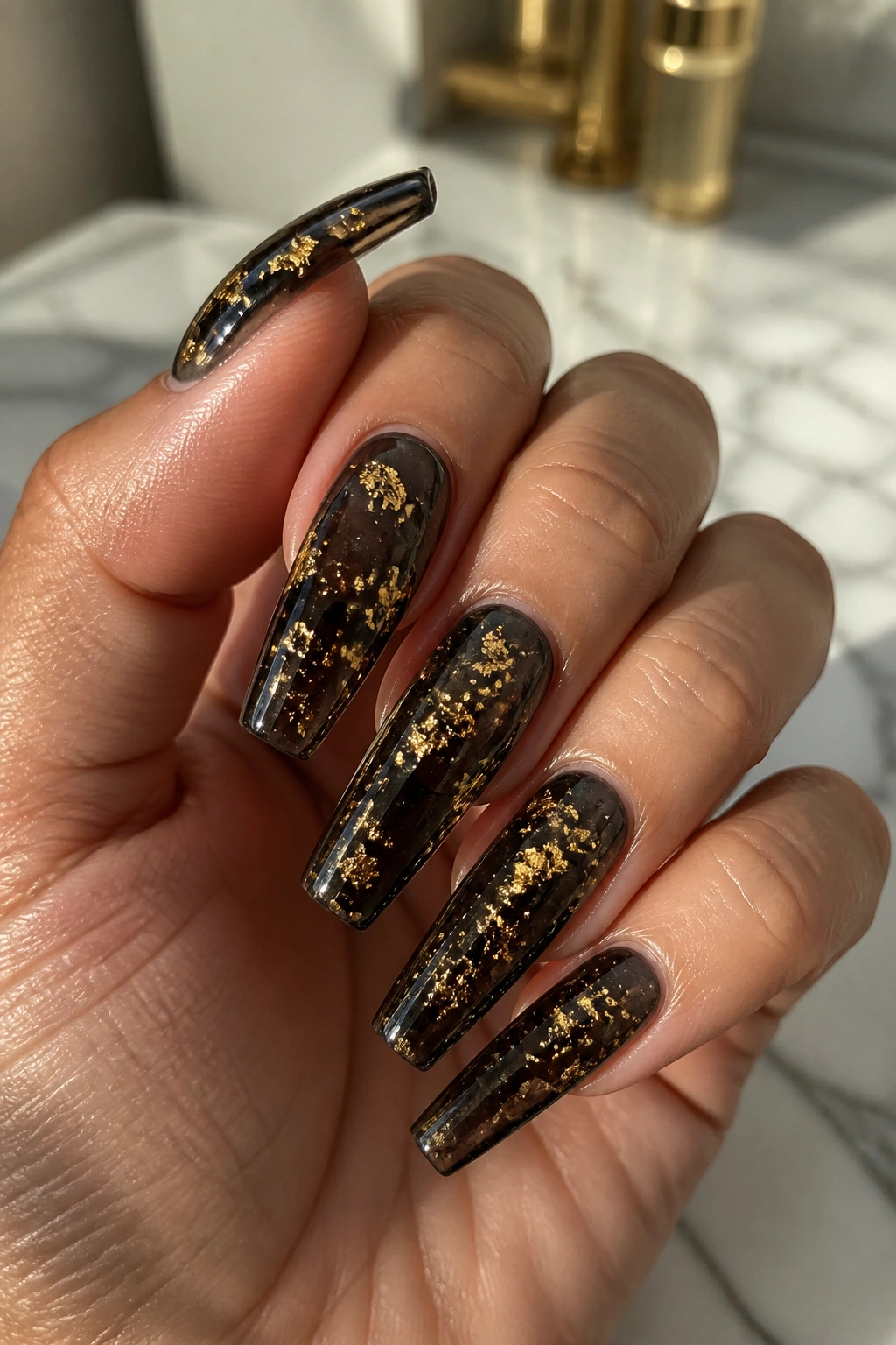 Close-up of jelly black coffin nails with encapsulated gold flakes