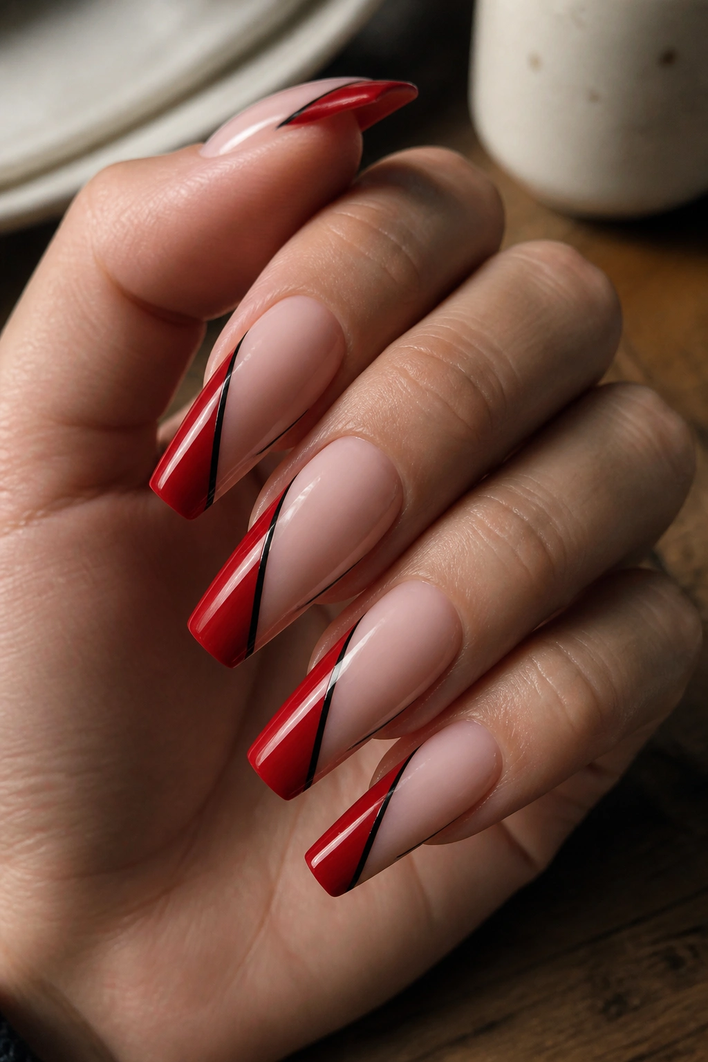 Coffin nails with black-lined red side-swipe on nude base in a natural setting