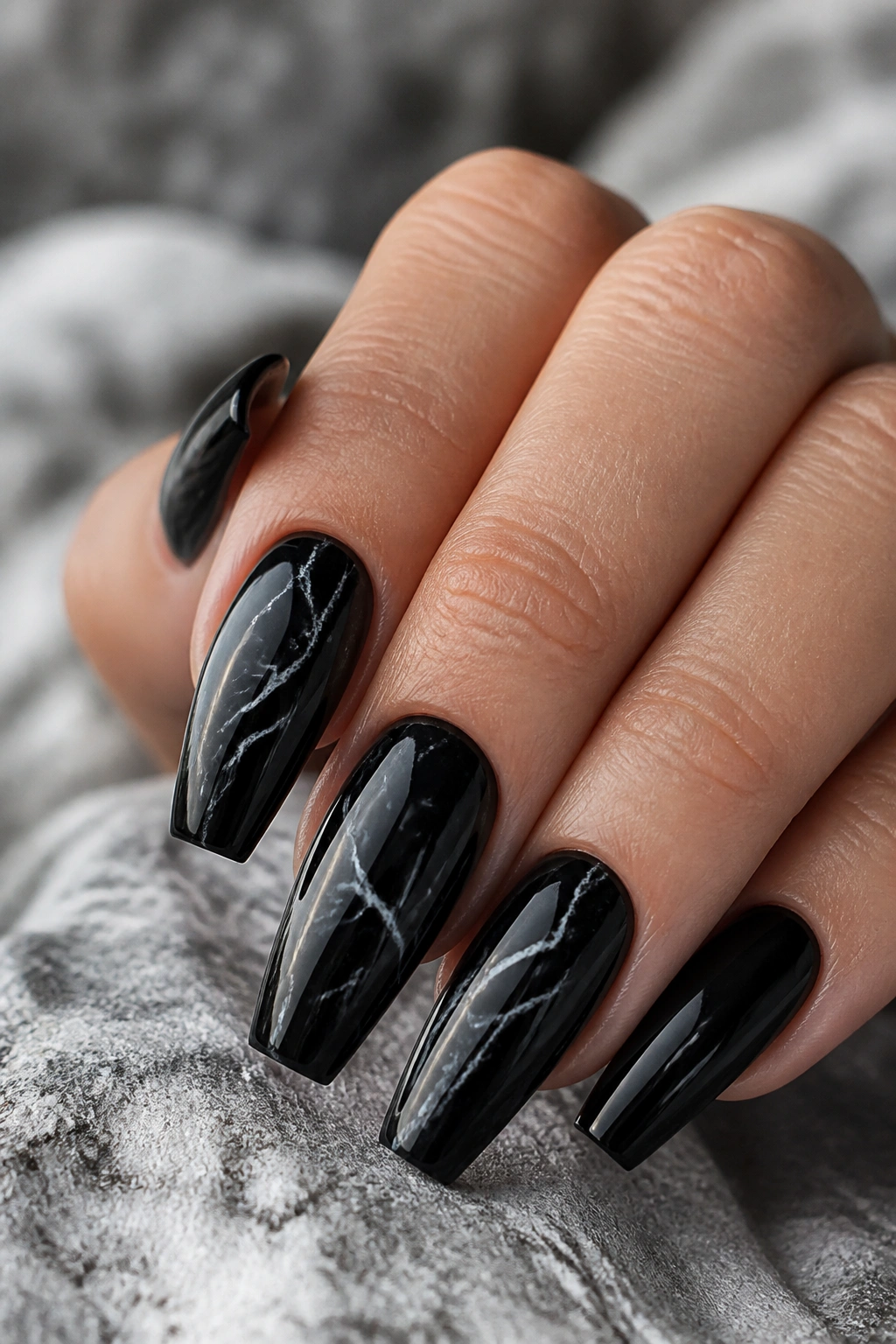 Close-up of black marble coffin nails with gray veining on a real hand.