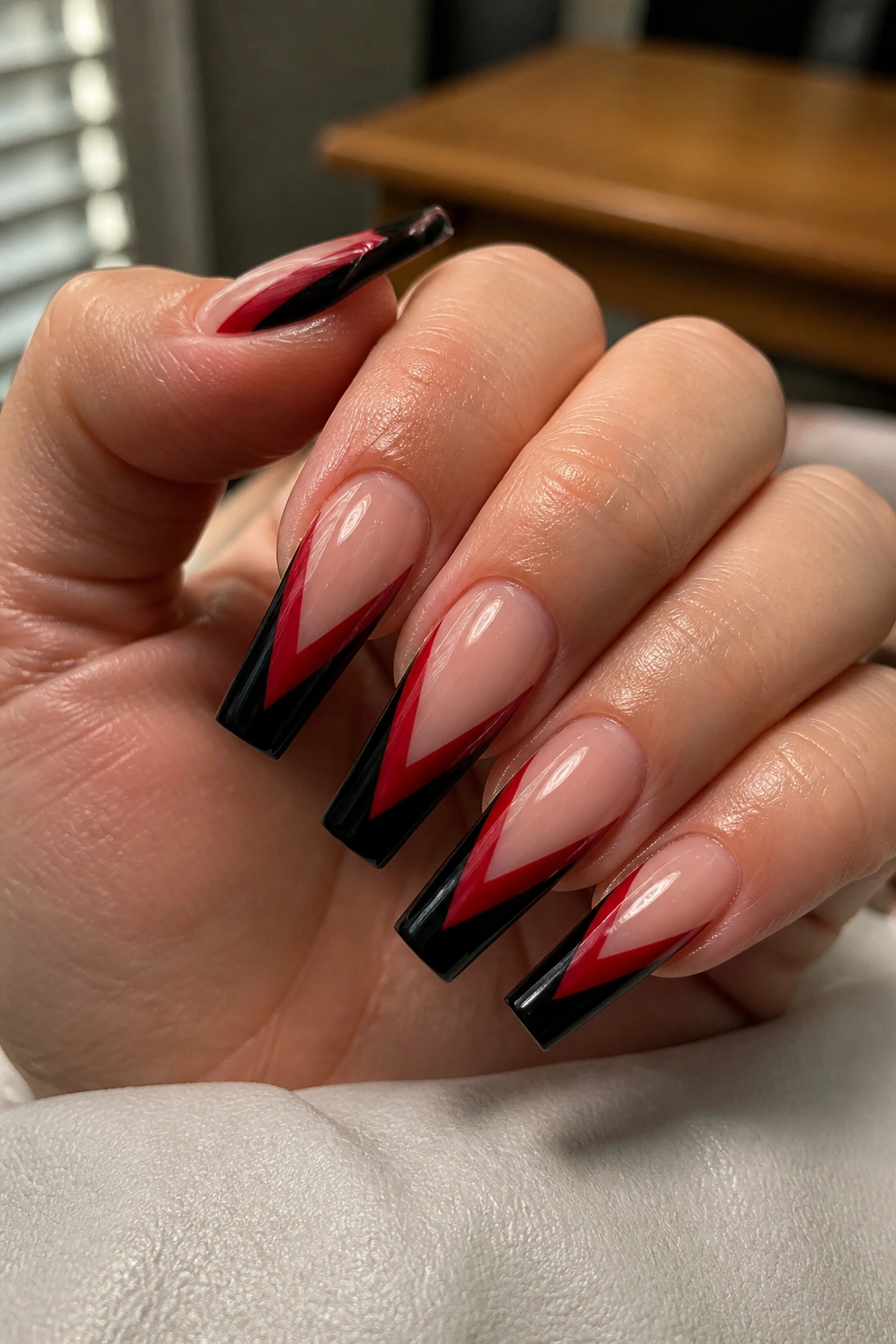 Close-up of hand with coffin nails featuring black V-tips and red negative-space panels