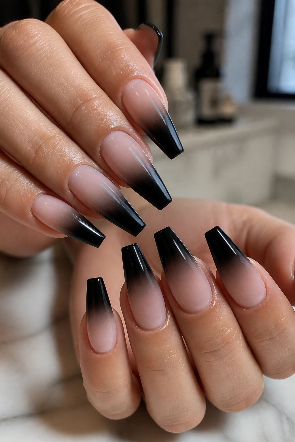 Close-up of hands with black-to-nude ombre coffin nails and crisp flat tips in natural light