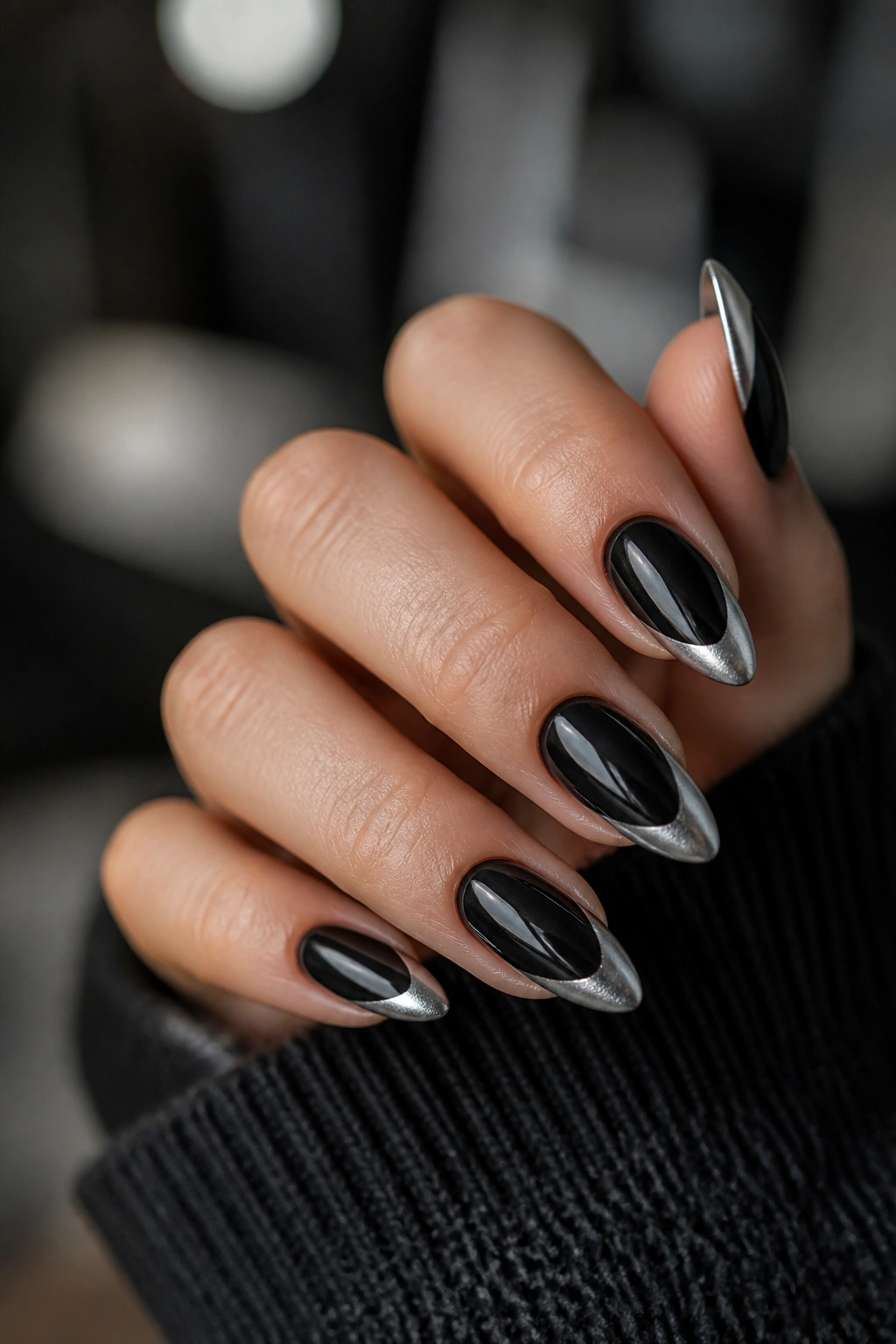Close-up of almond nails with black and silver contrast design