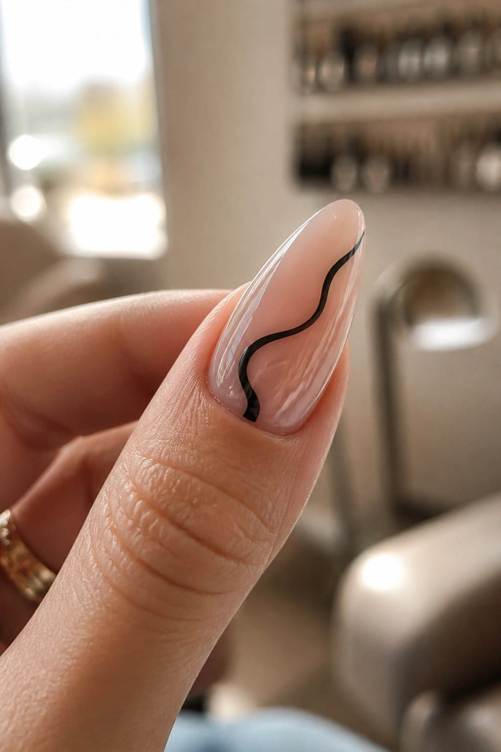 Close-up of almond nail with sheer milky base and single black swirl