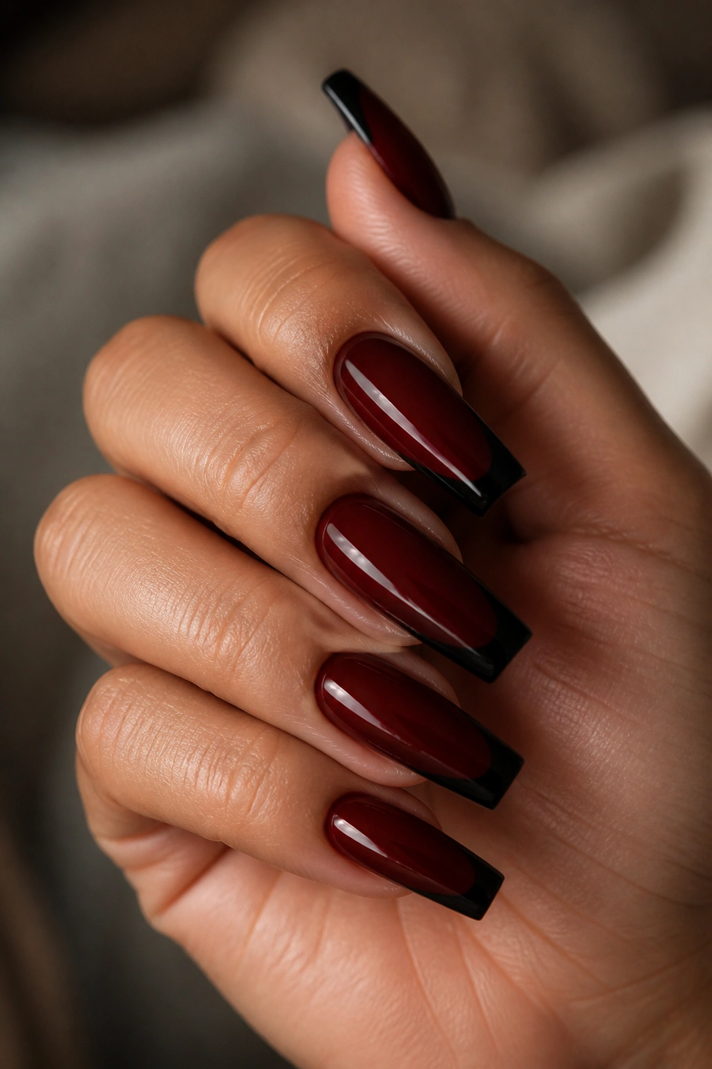 Close-up of black French tip coffin nails on a deep cherry base