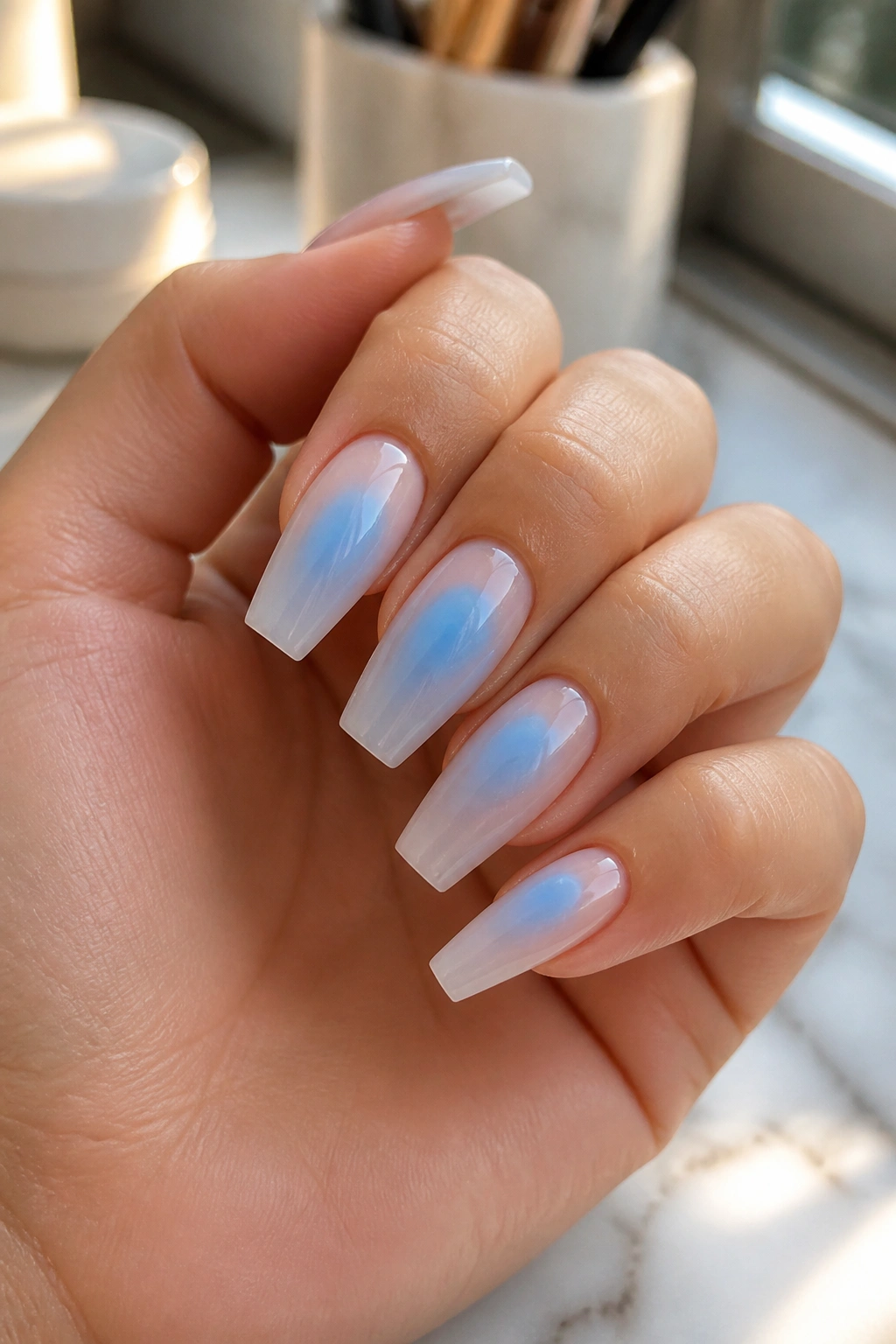 Close-up of coffin nails with baby blue aura centers on a sheer base