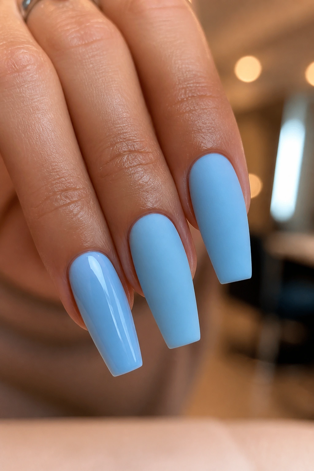 Close-up comparing glossy and matte blue coffin nails on a real hand