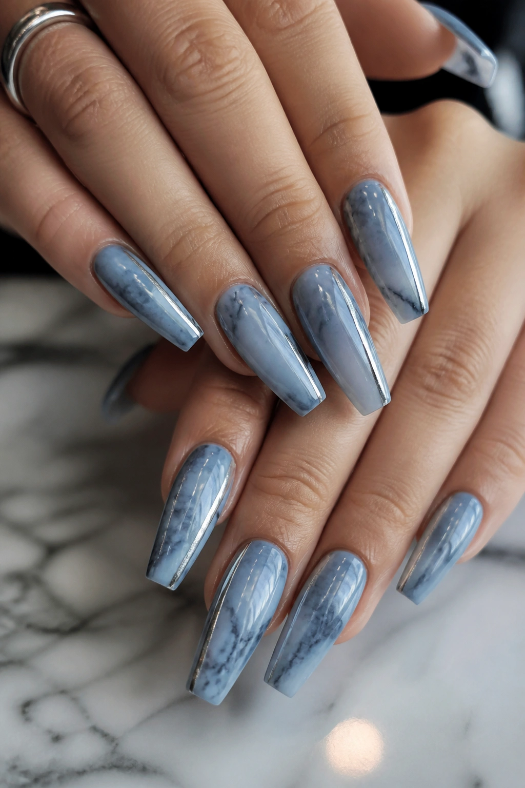 Close-up of blue-gray marble coffin nails with a silver chrome line on a real hand