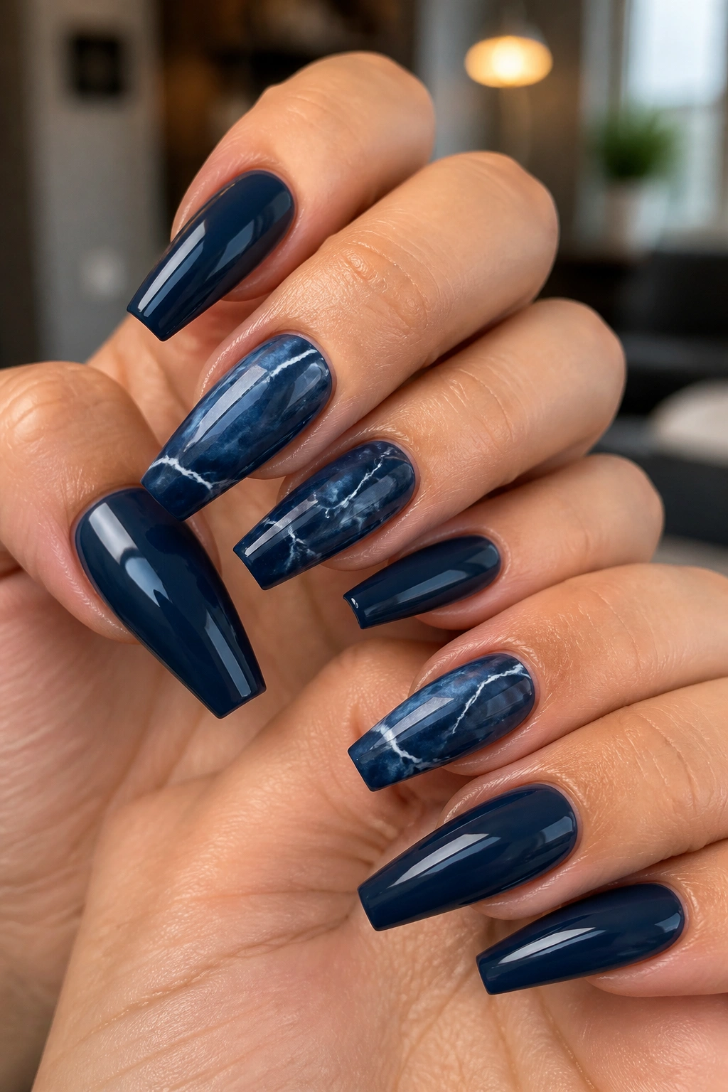 Blue marble coffin nails with fine white veining on real hands in a studio