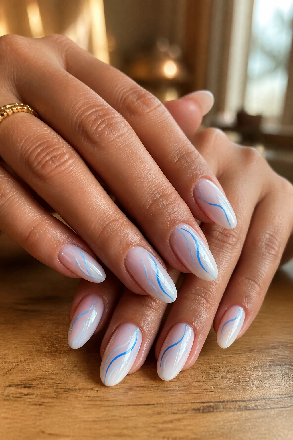Close-up of almond nails with blue and white wave line art on a real hand in a salon setting