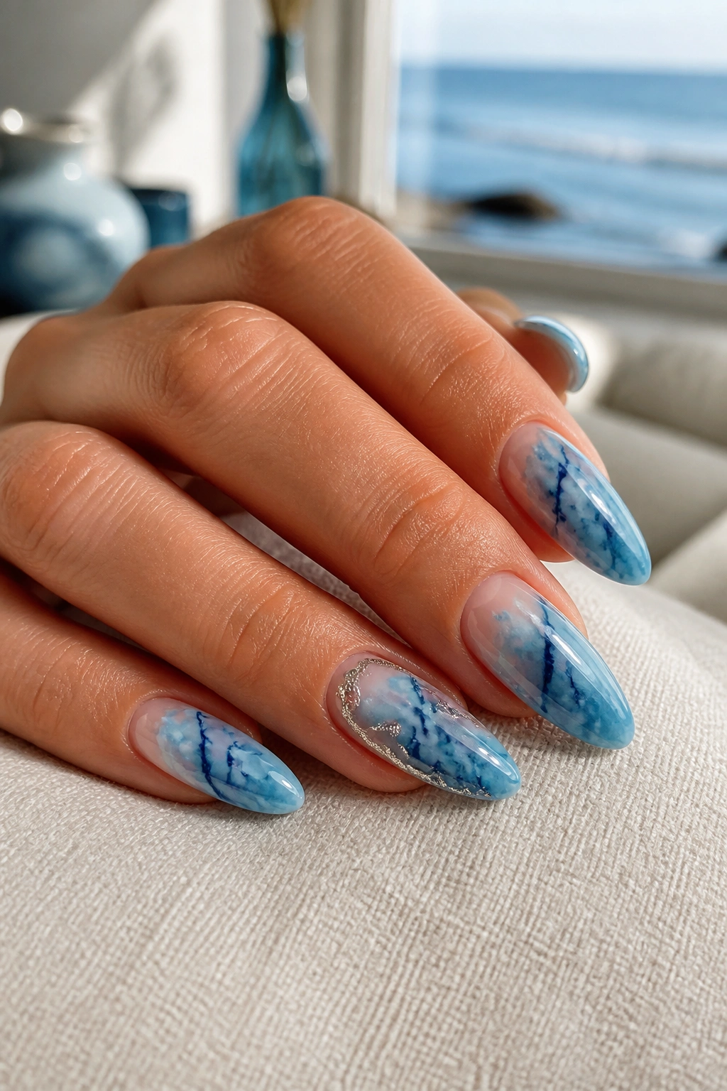 Almond nails with blue tide marble and sea-glass depth on a real hand