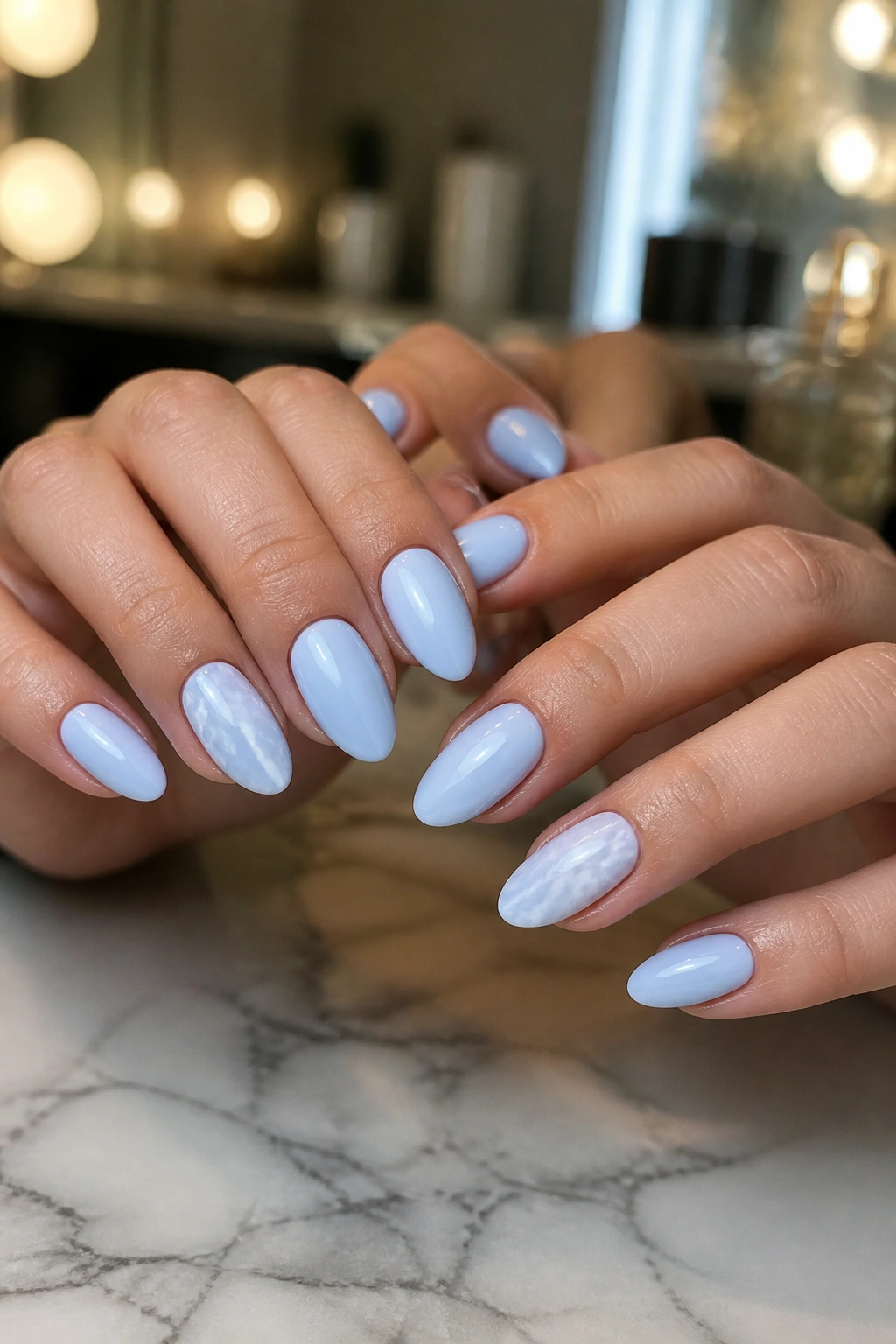 Almond nails with baby blue base and white marble swirls on accent nails
