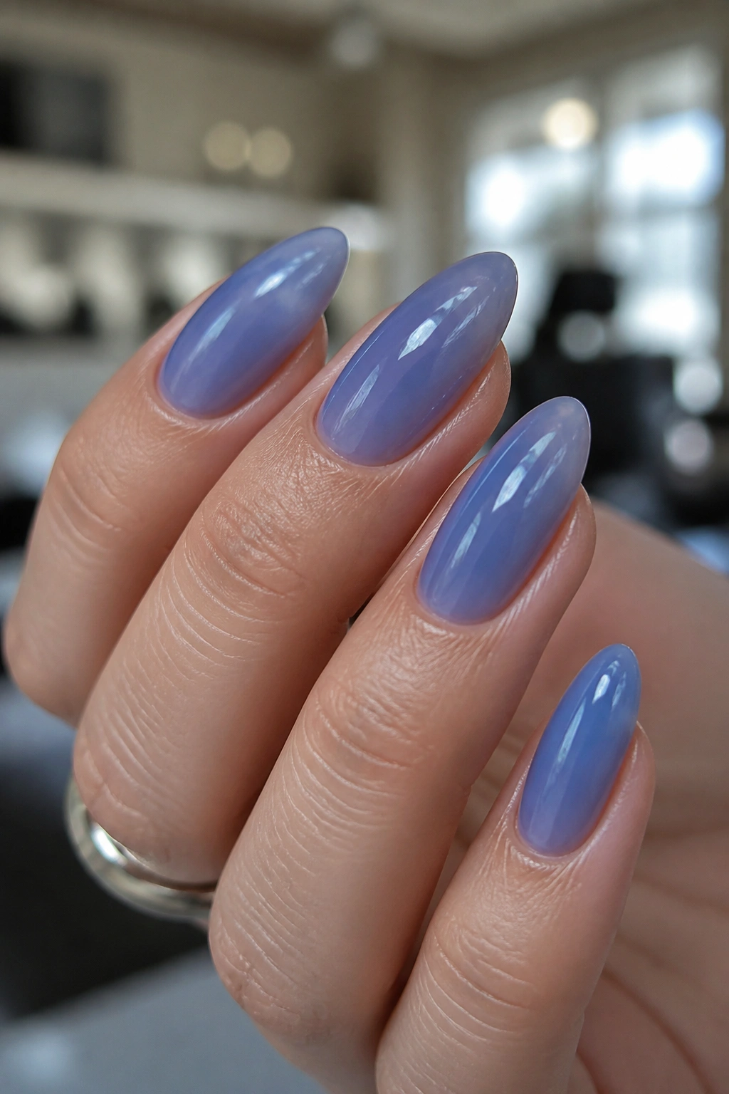 Close-up of an almond nail with translucent blueberry jelly finish in a salon setting