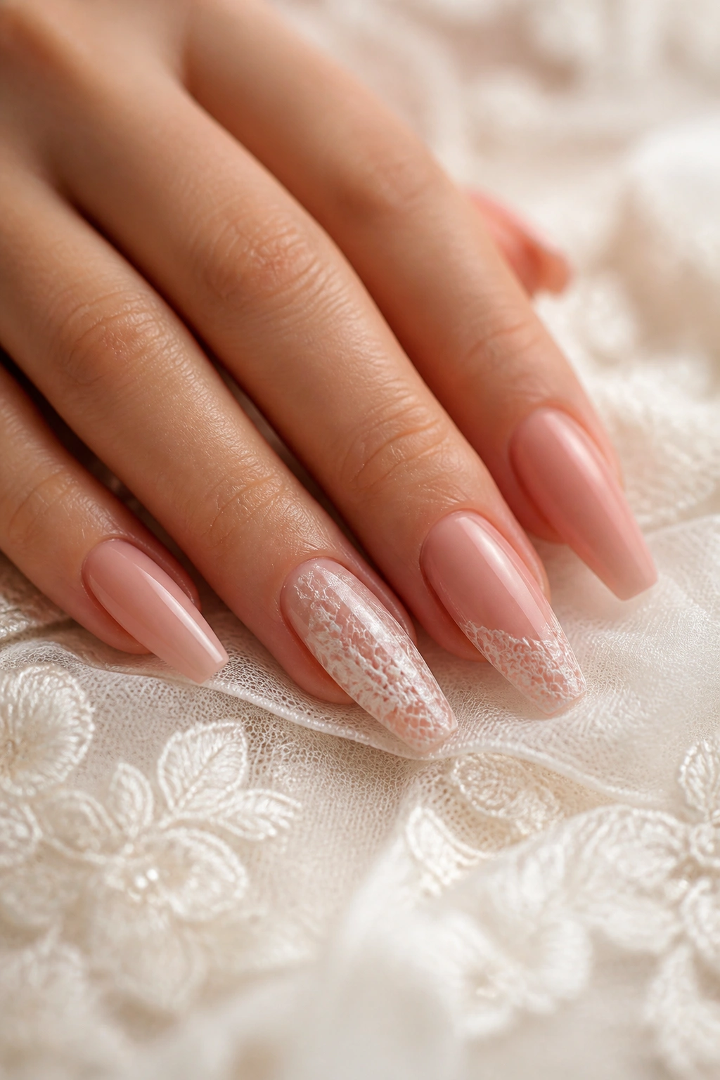 Close-up of blush coffin nails with hand-painted lace on a real hand