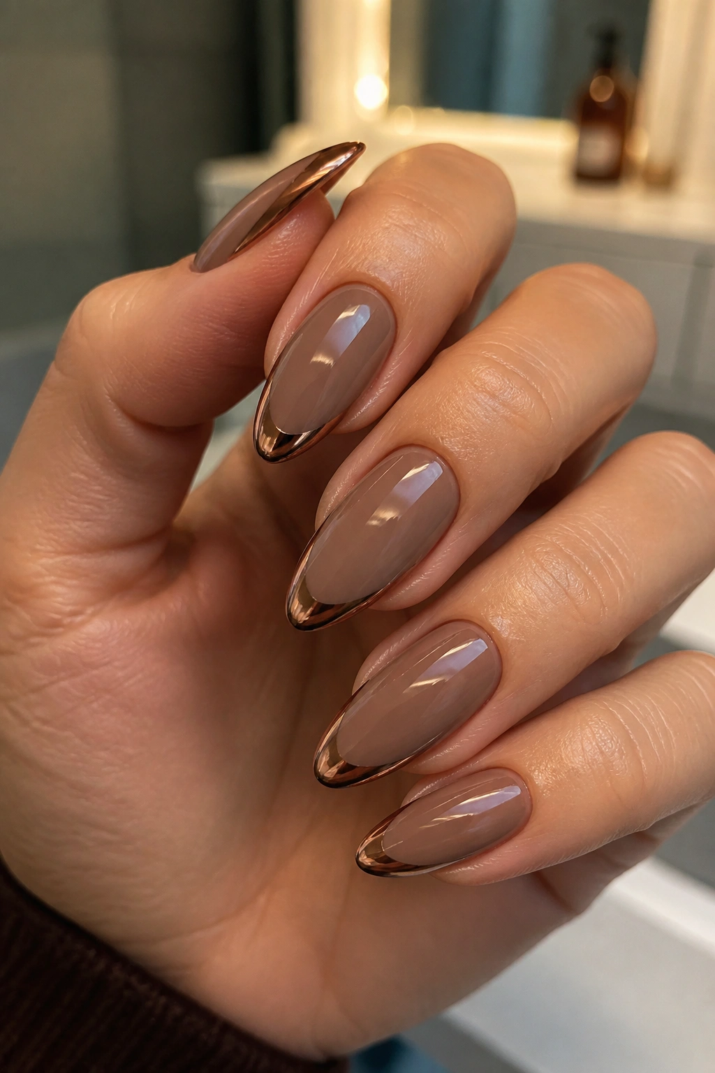 Close-up of almond nails with brown chrome French tips on a brown base