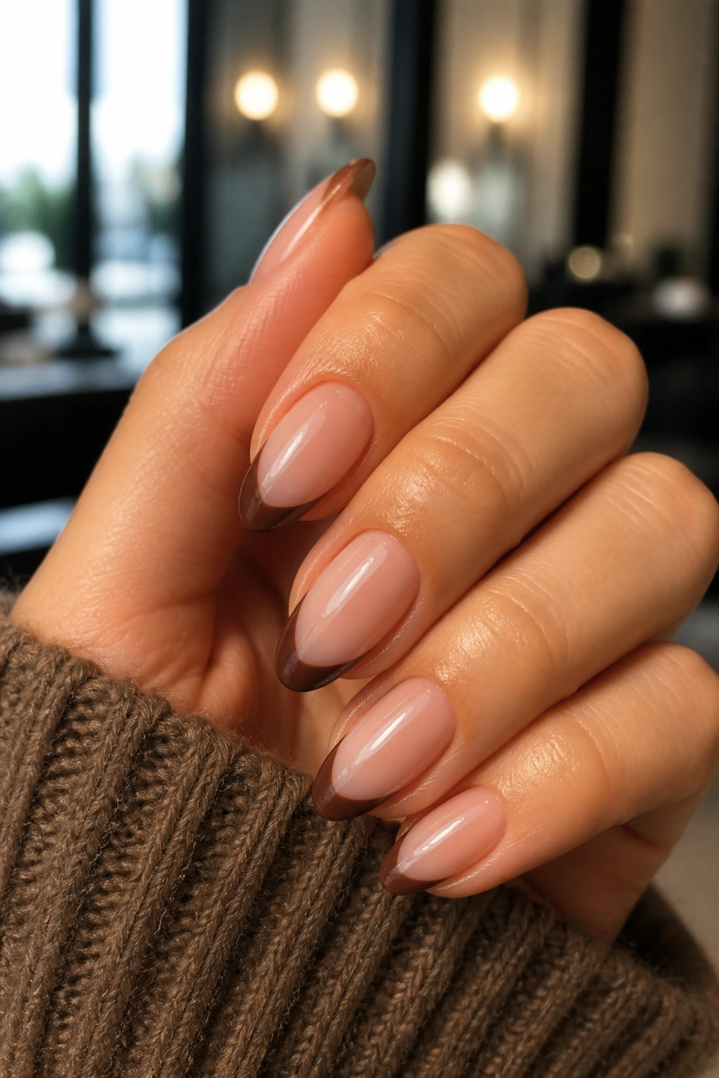 Close-up of almond nails with side-swept brown French tips