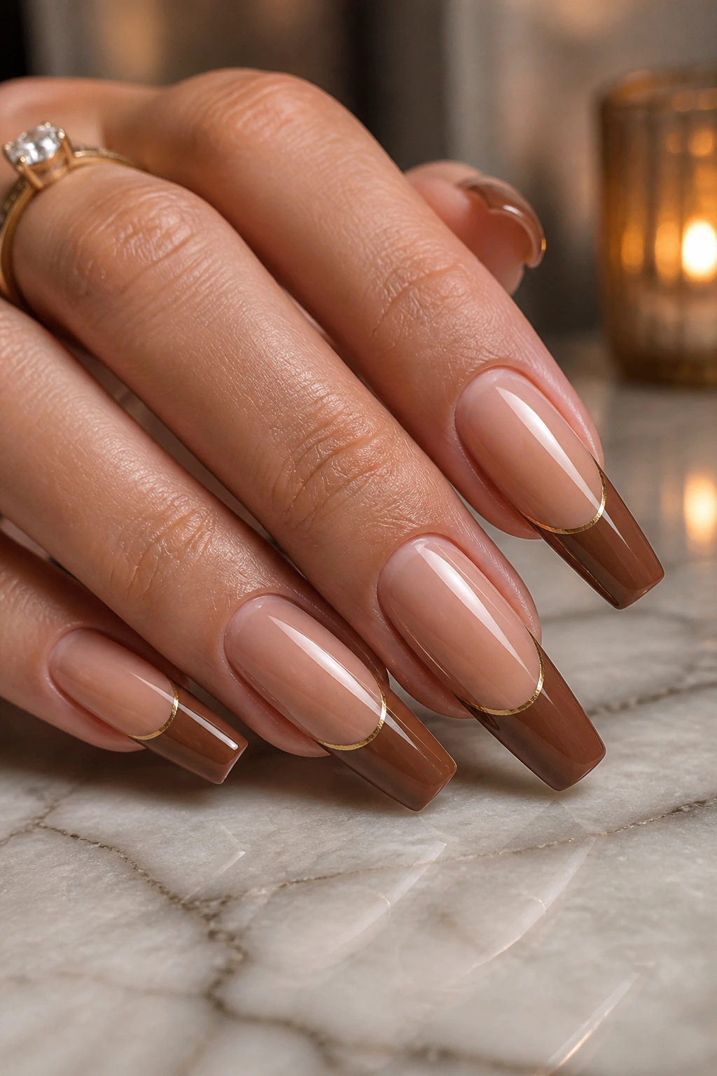 Close-up of brown tips with a thin gold divider on coffin nails