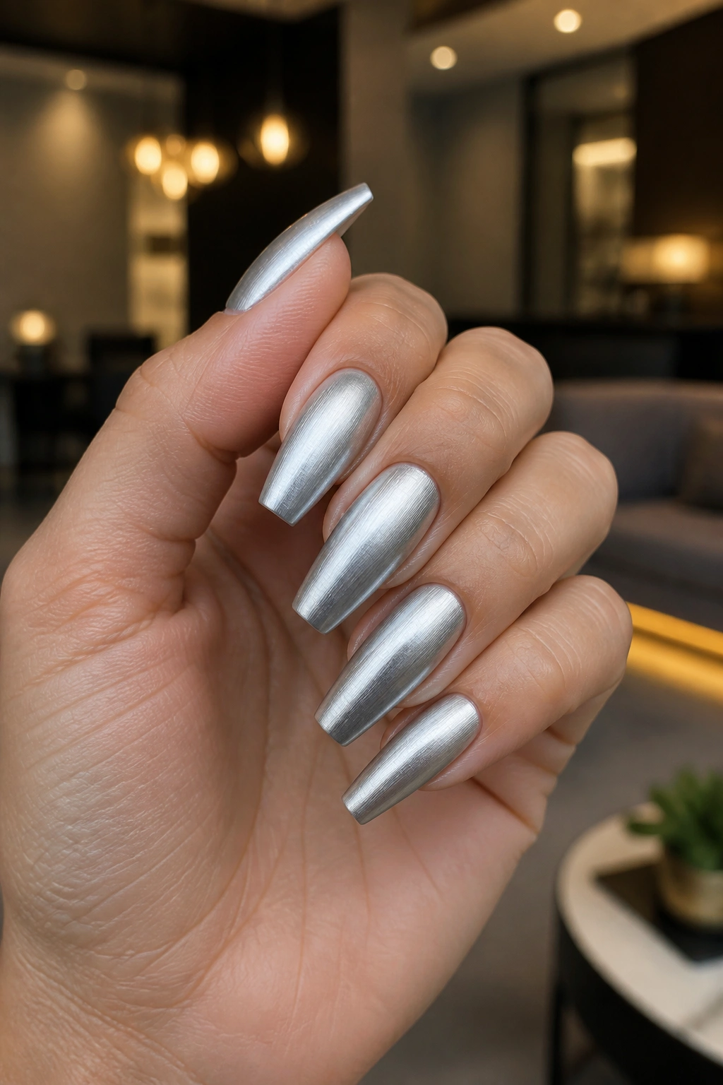 Close-up of brushed-metal silver coffin nails on real hand