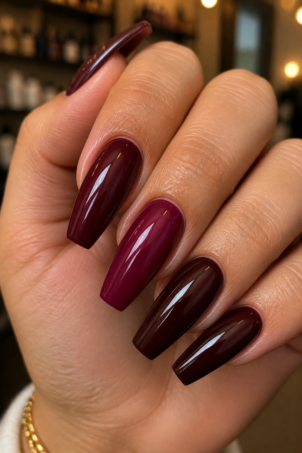 Close-up of a hand with coffin nails in deep wine, berry, and oxblood burgundy shades.