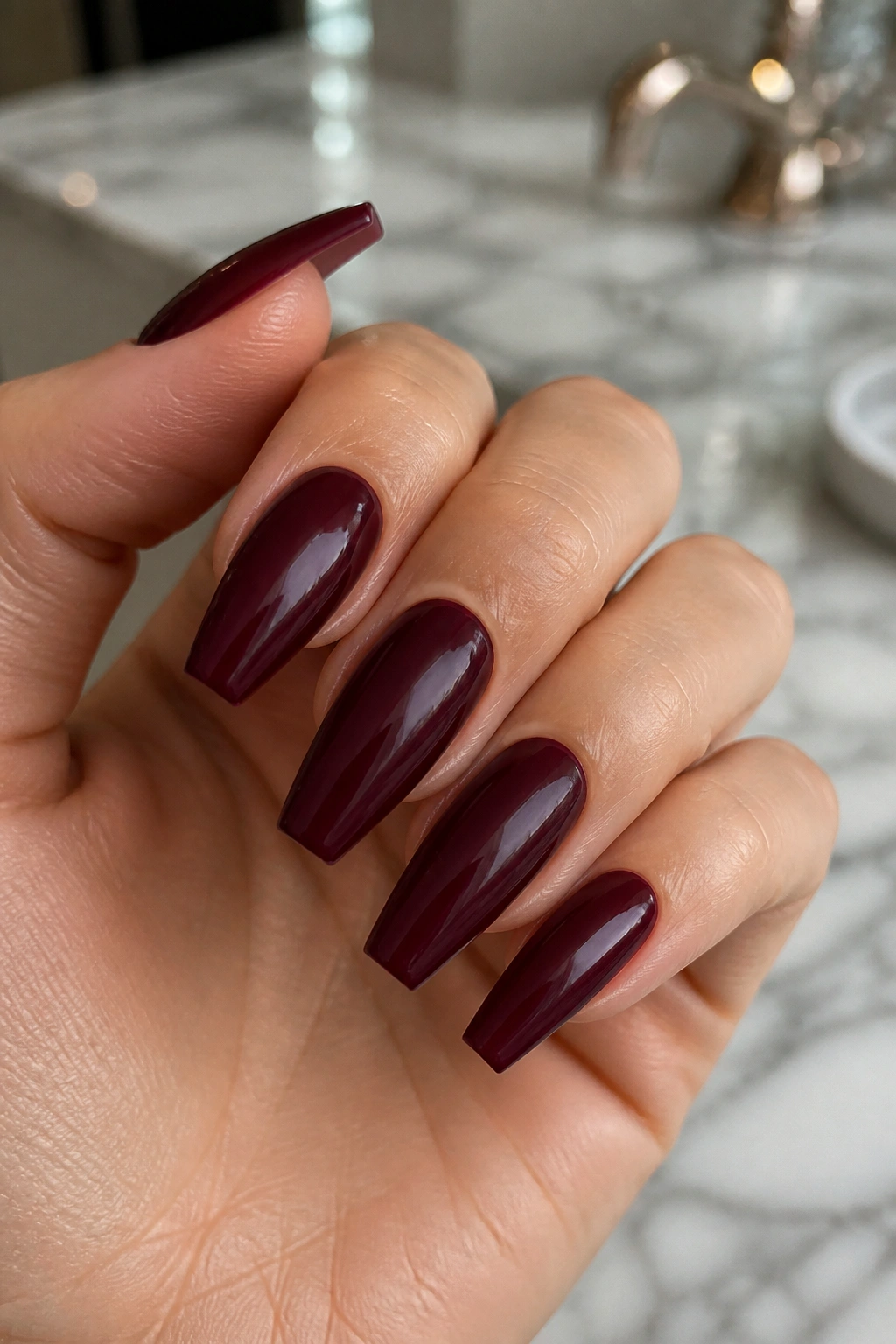 Close-up of deep burgundy coffin nails on real hand