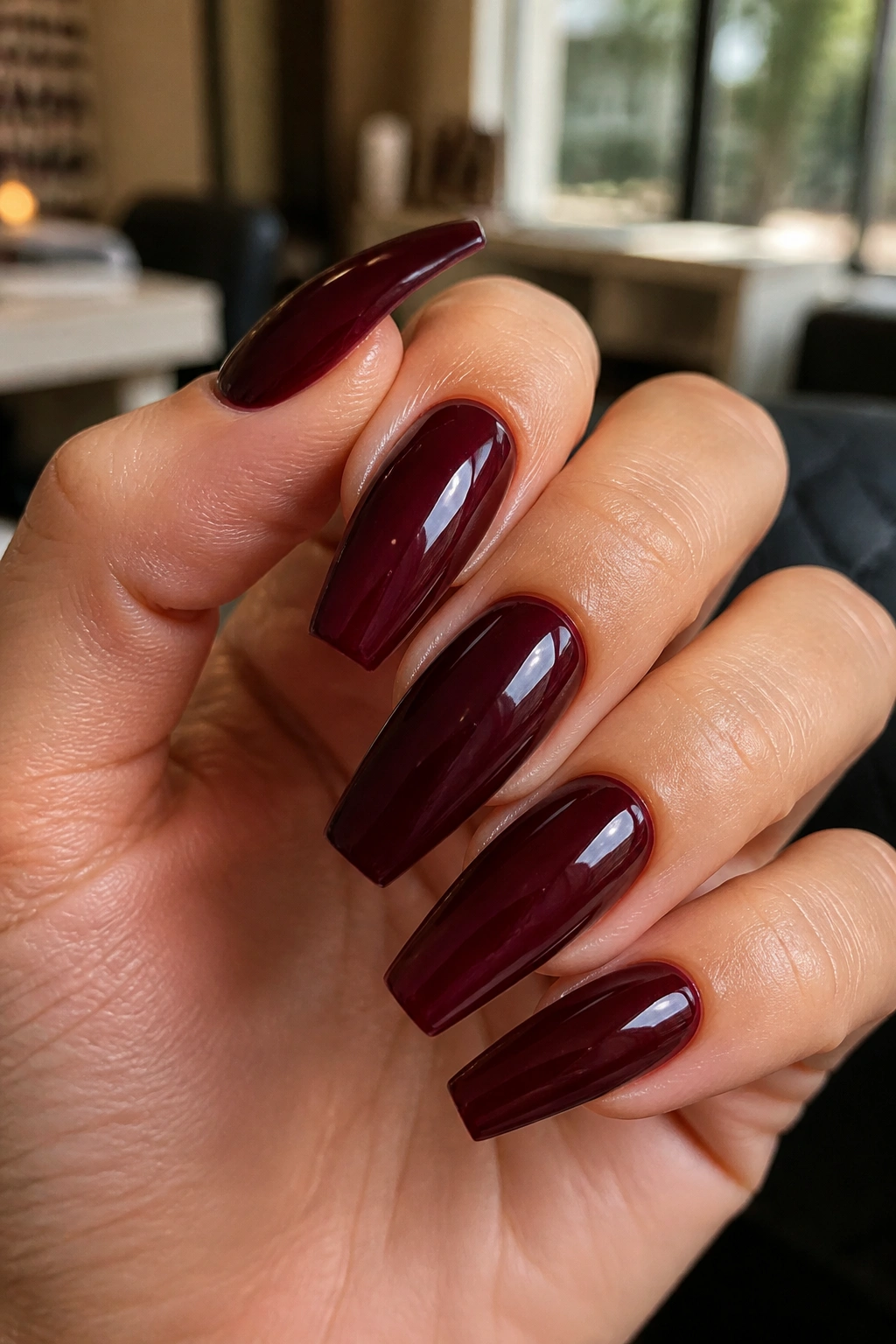 Close-up of burgundy coffin nails with a glossy finish on a real hand