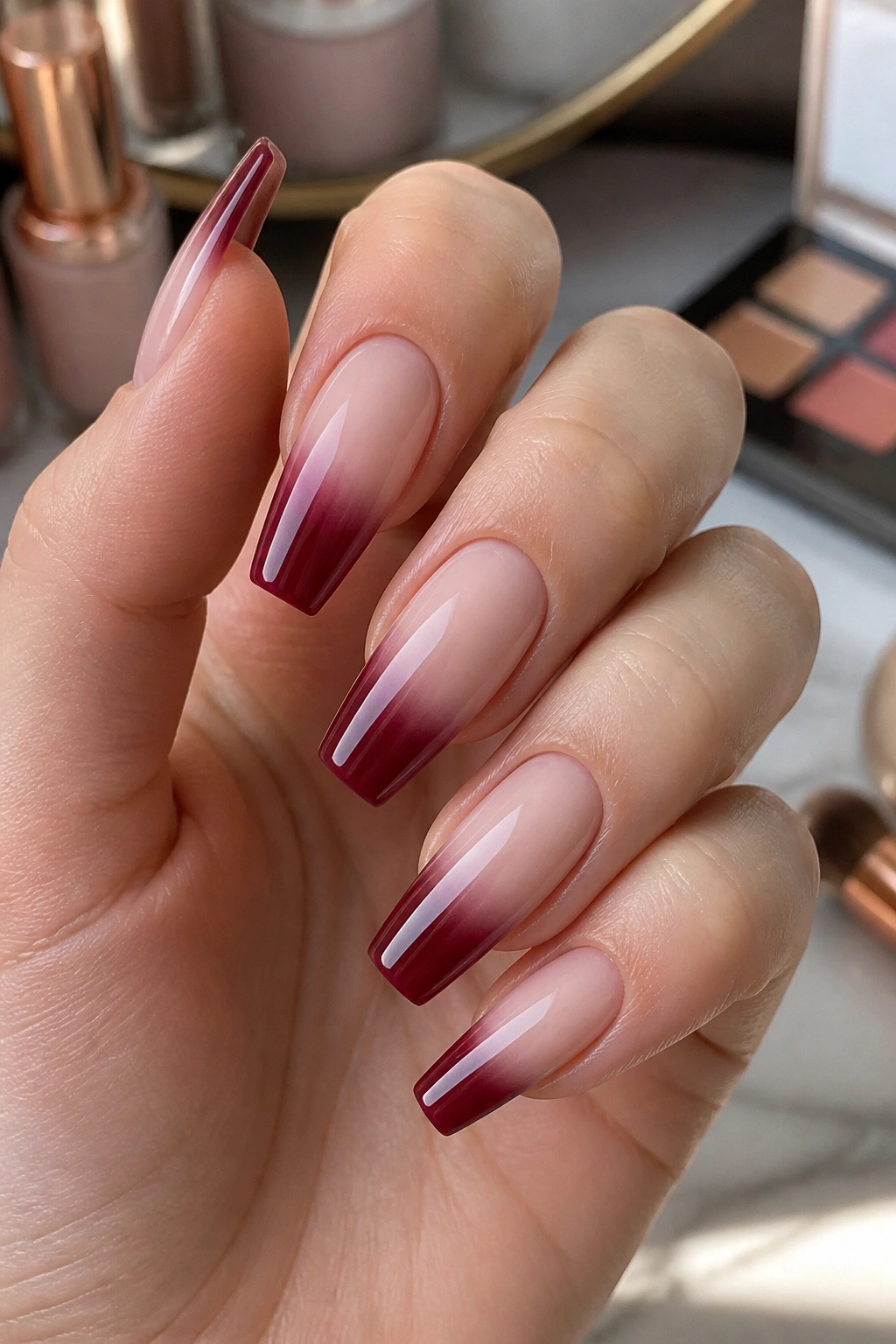 Close-up of burgundy French fade coffin nails on milky nude base