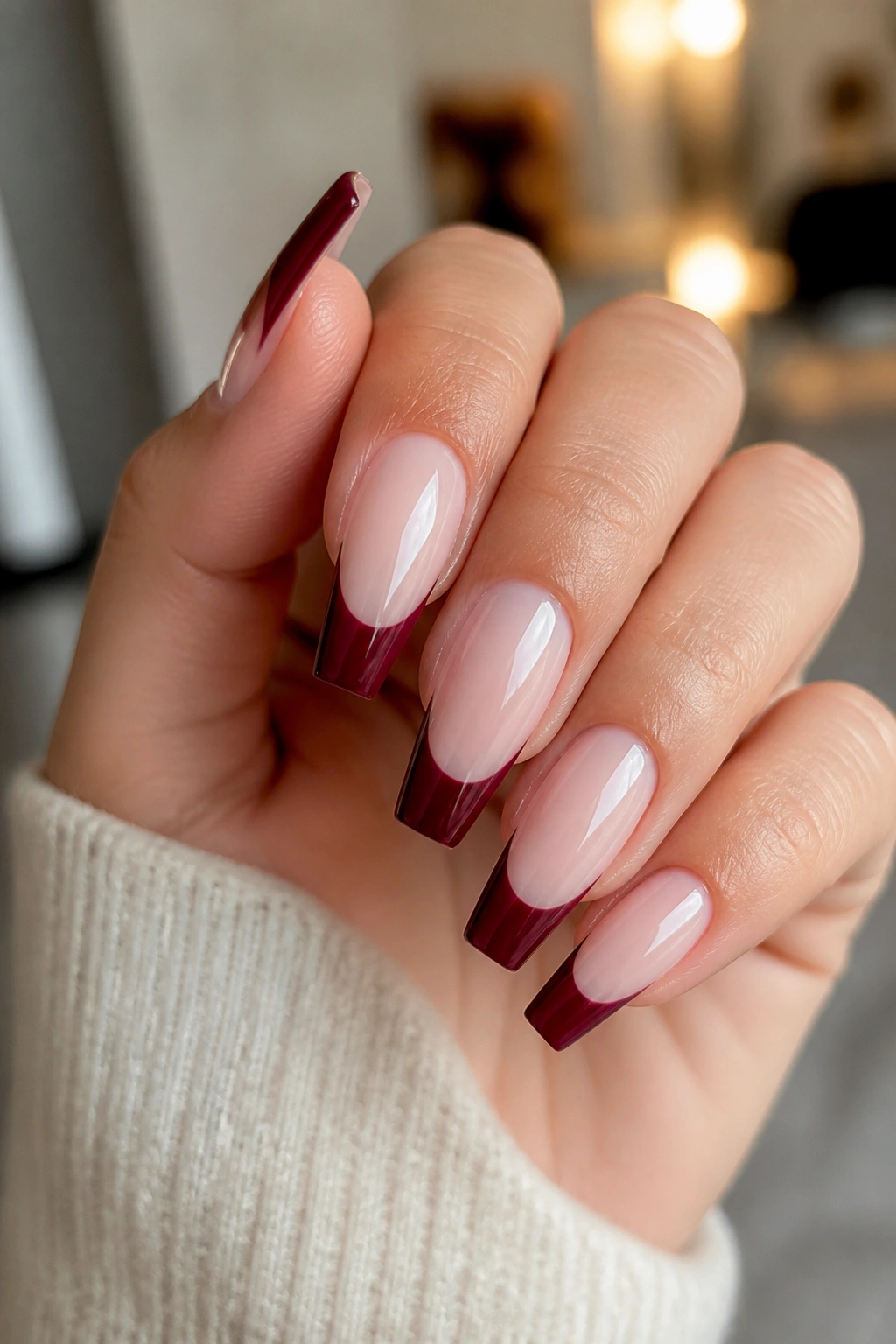 Close-up of burgundy French tip coffin nails on milky nude base with crisp tip line.