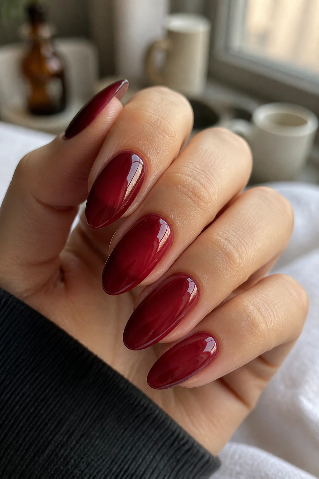 Close-up of burgundy jelly almond nails on a real hand with translucent glaze
