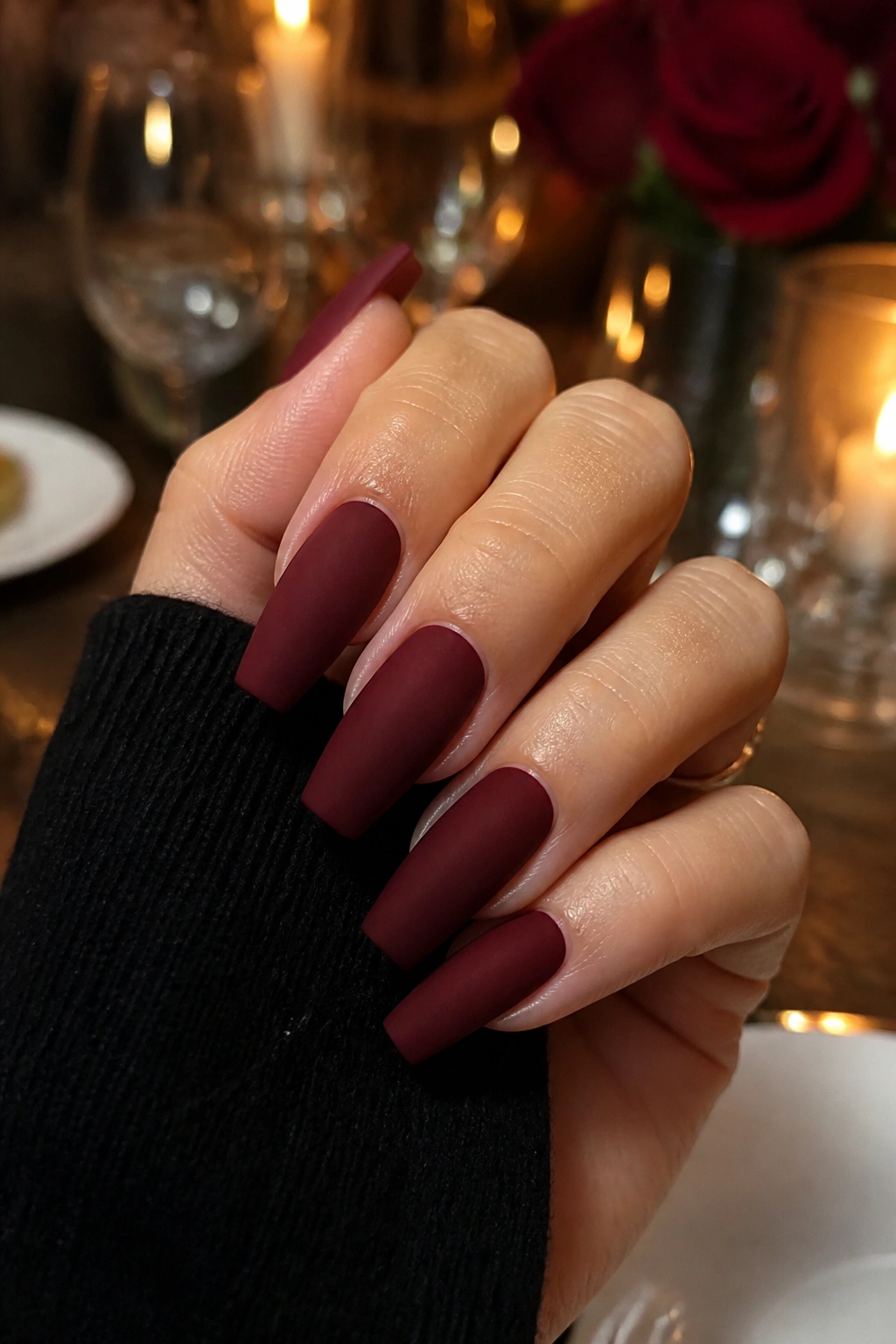 Close-up of deep burgundy matte coffin nails on real hand.