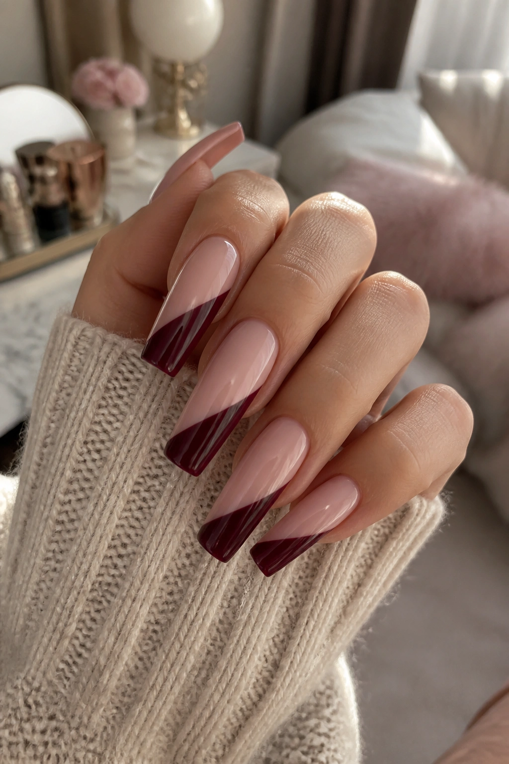 Close-up of burgundy and blush color-block coffin nails on a real hand