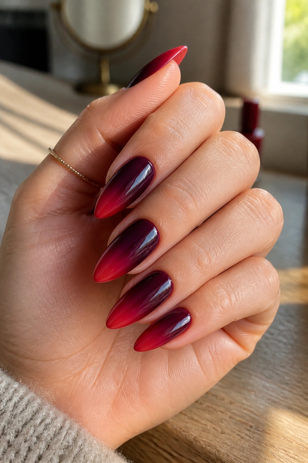 Close-up of burgundy ombré almond nails on a real hand with gradient from deep wine to red