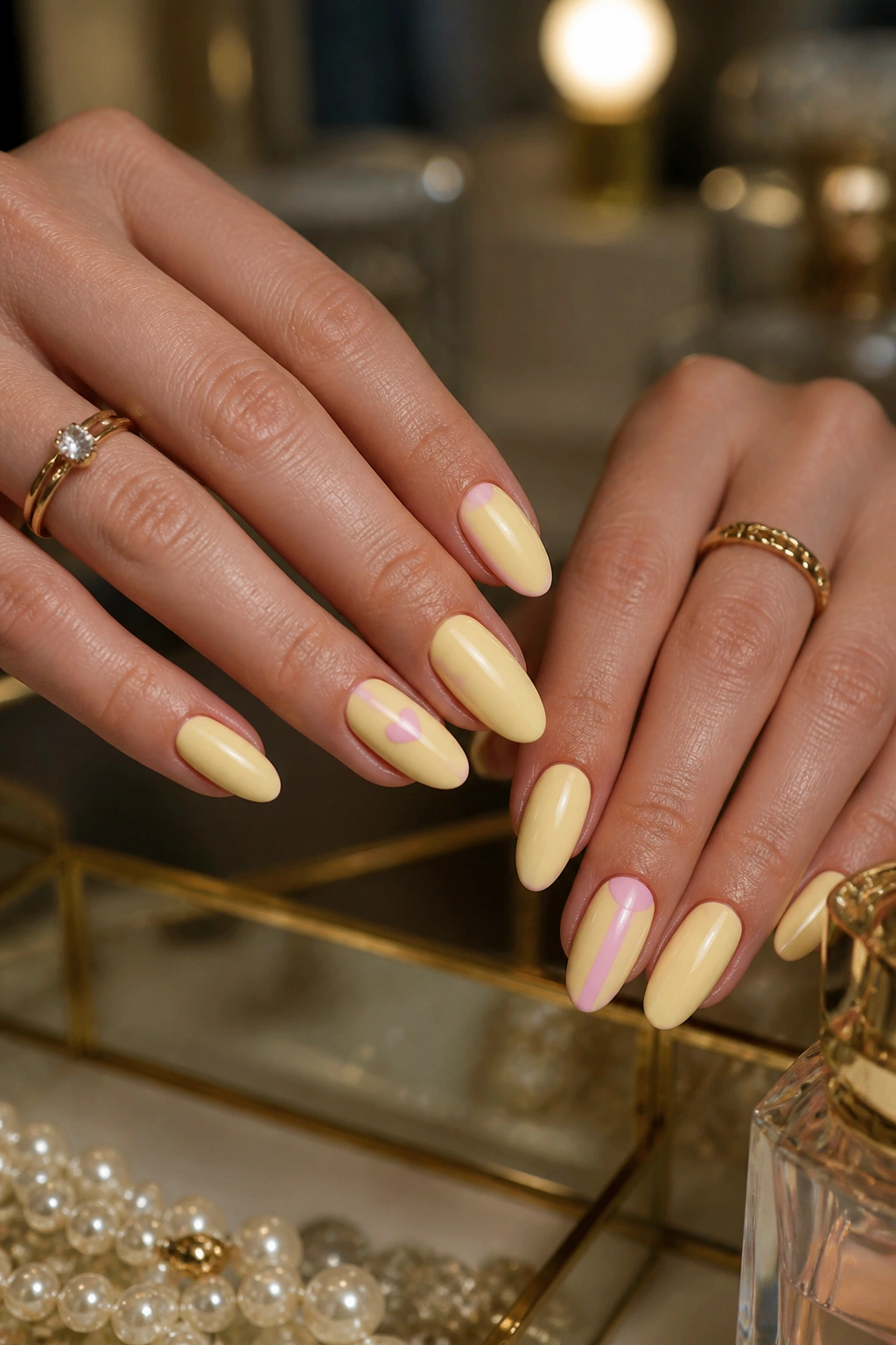 Close-up of almond nails in butter yellow with blush pink accent details