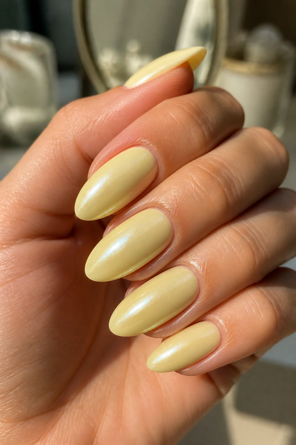 Close-up of almond nails with butter-yellow chrome glaze on a real hand
