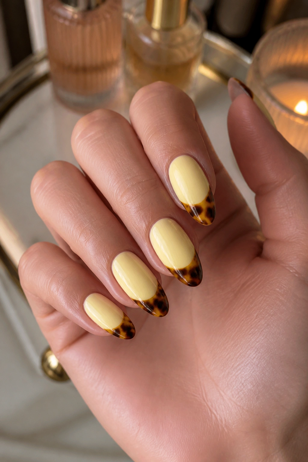 Close-up of almond nails with butter yellow base and tortoiseshell tips